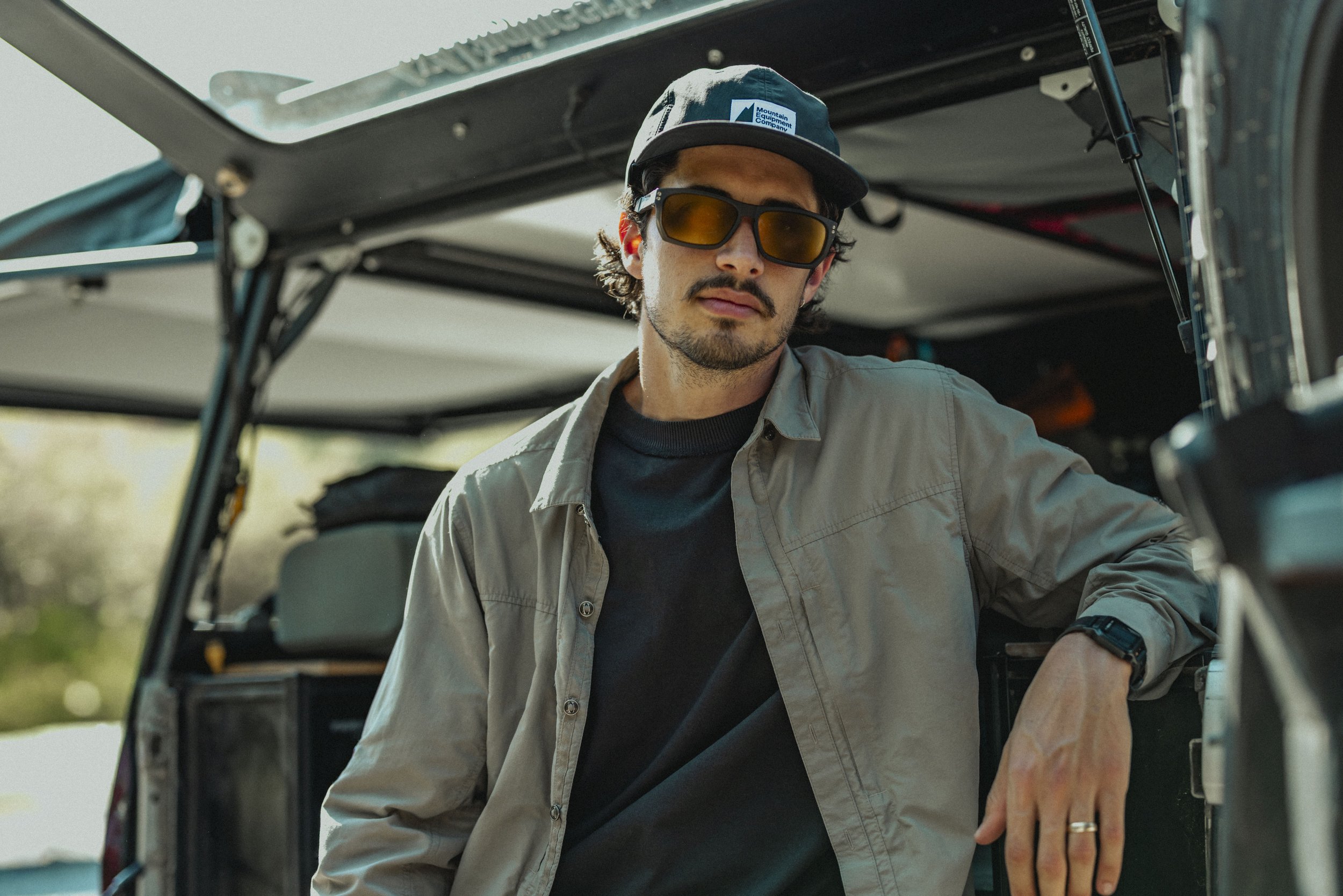 A man with sunglasses and a cap sitting in a utility vehicle, looking at the camera.