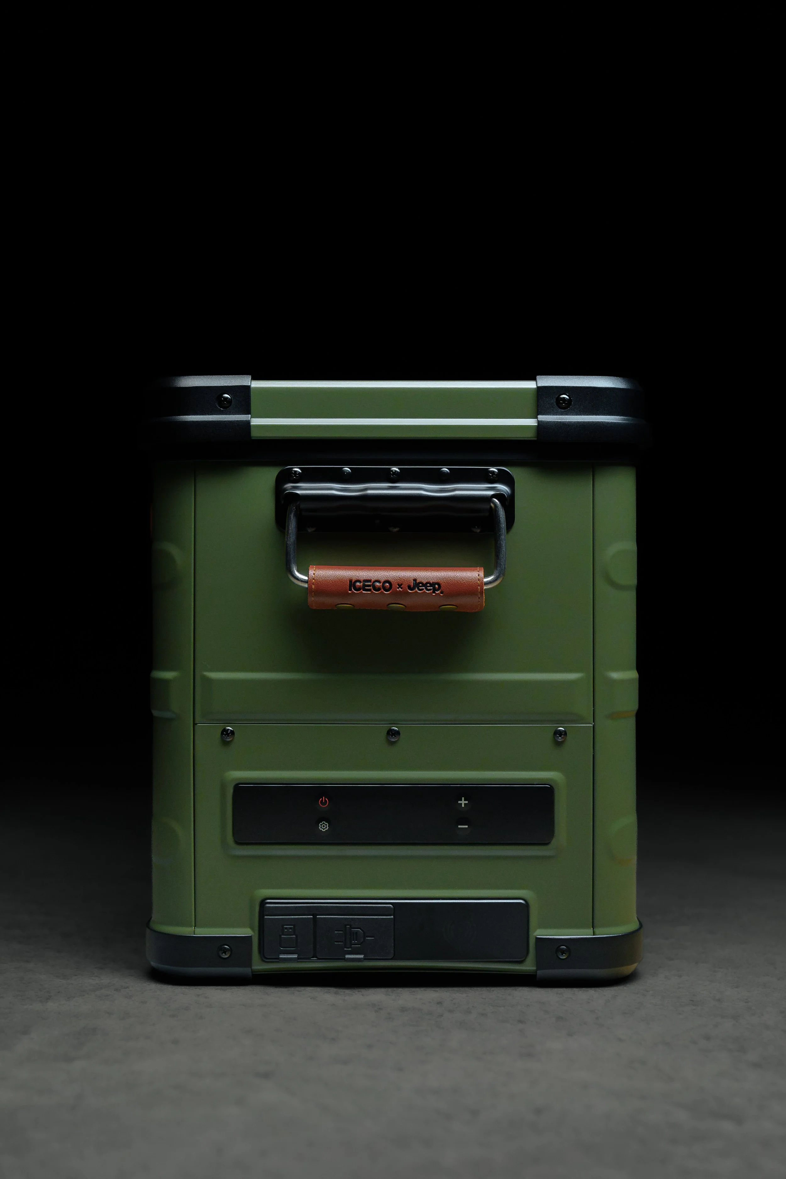 A small green portable refrigerator or cooler with digital control panel and metal handle, set against a dark background.