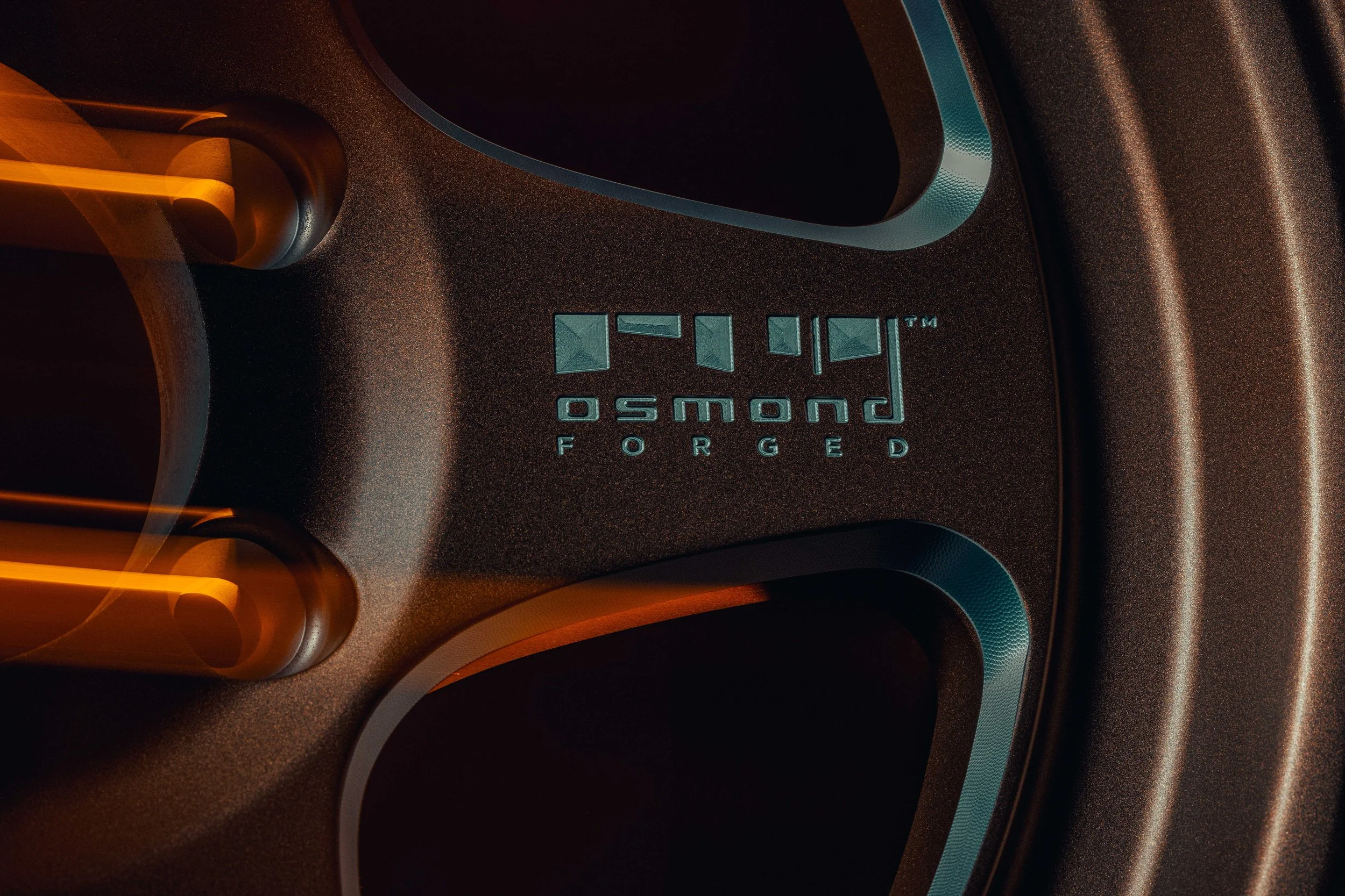 Close-up of a black speaker with a textured surface, featuring a metallic logo that reads 'POWERSO' and the word 'FORGED' underneath, with orange and teal accents surrounding it.