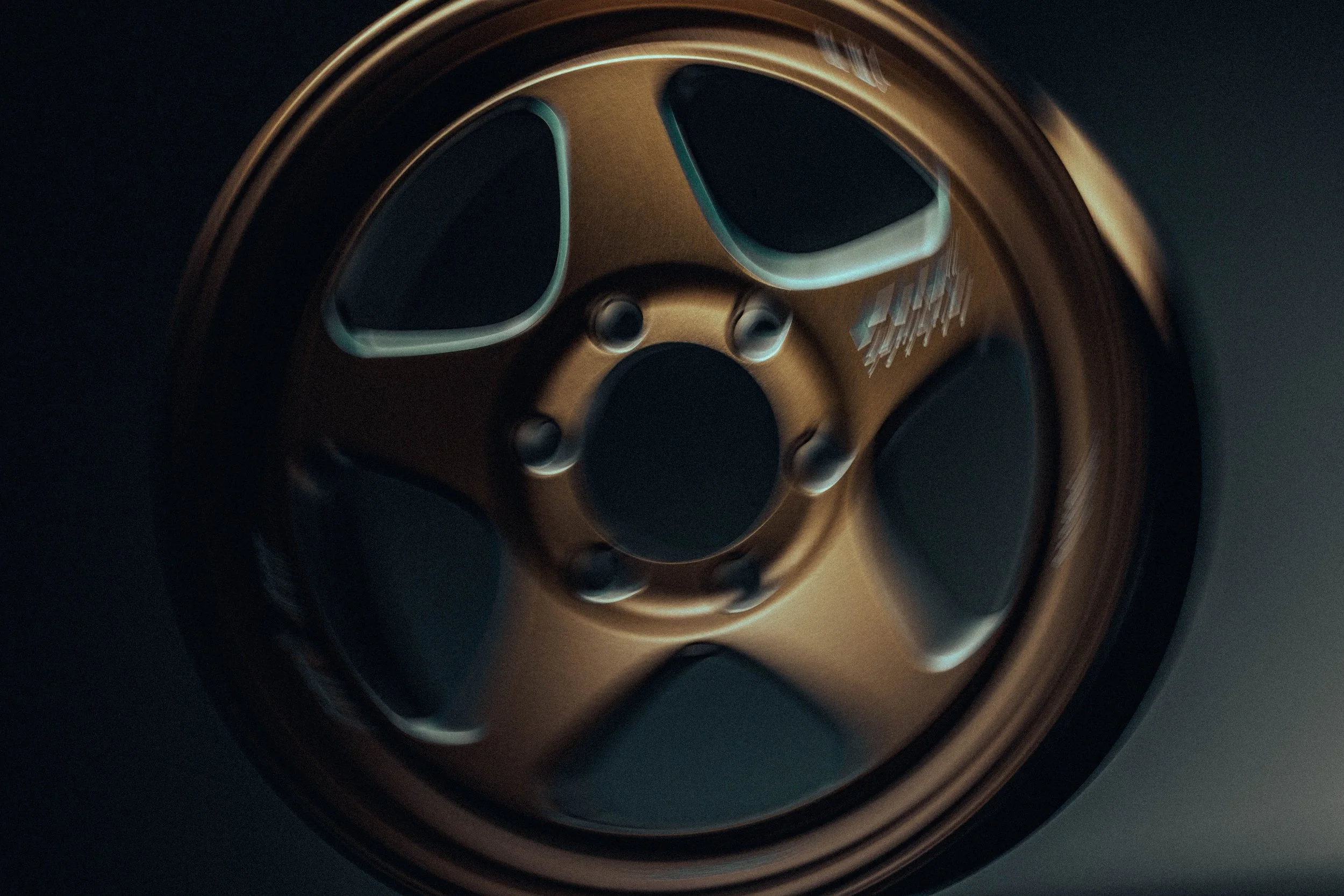 Close-up of a car wheel with a metallic rim and tire in a dark setting.