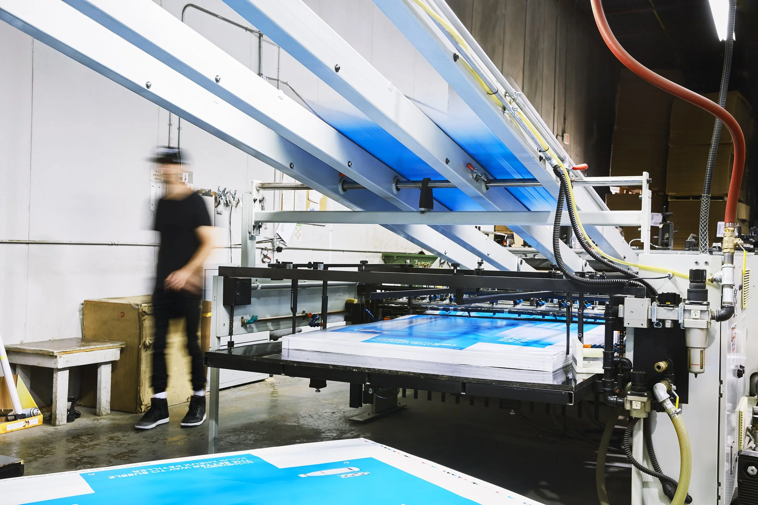 Art-directed brand photography for Proprint, featuring an employee working alongside industrial printing equipment at its production facility.