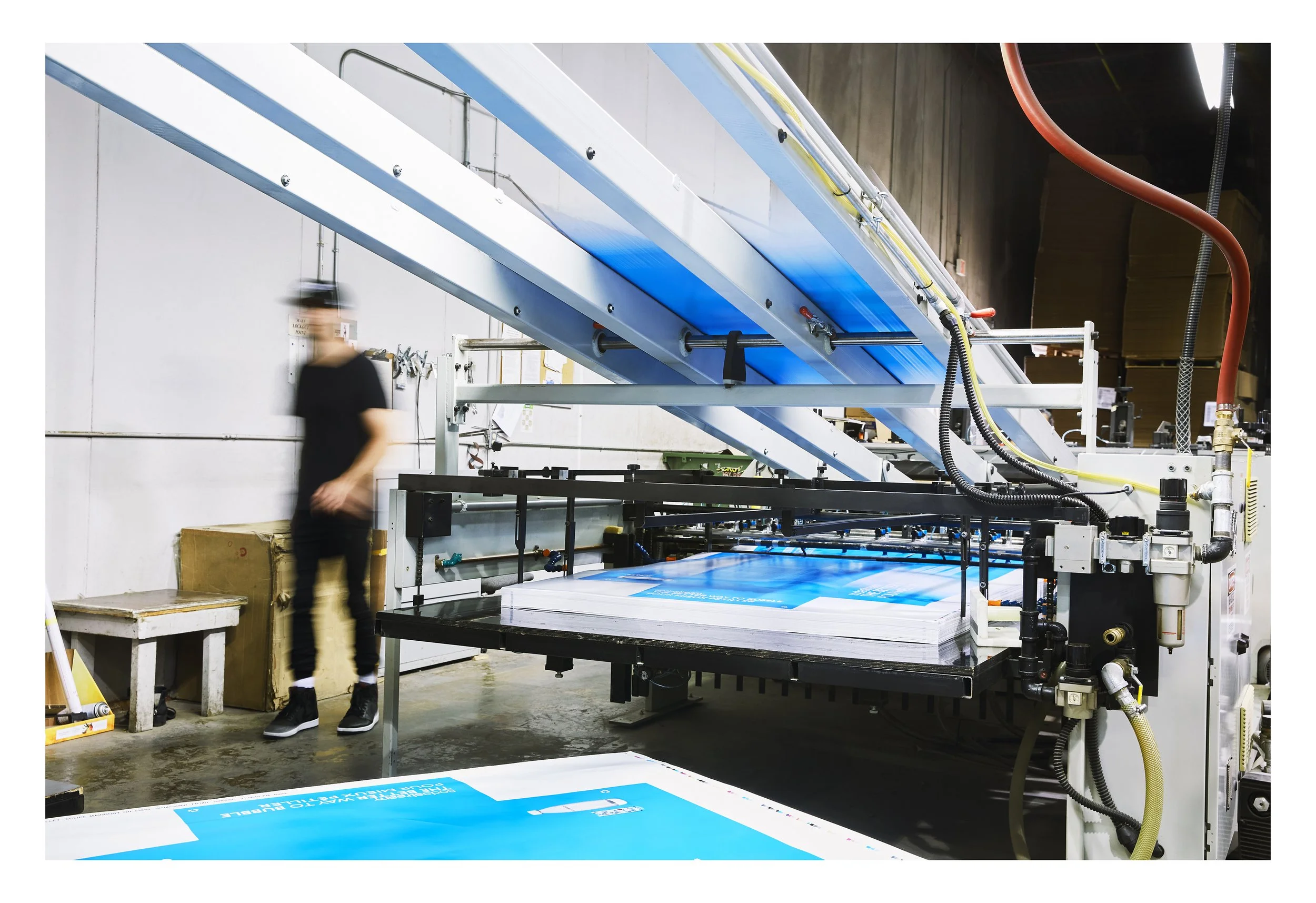Art-directed brand photography for Proprint, featuring large-format commercial printing equipment in operation with an employee at the production facility.