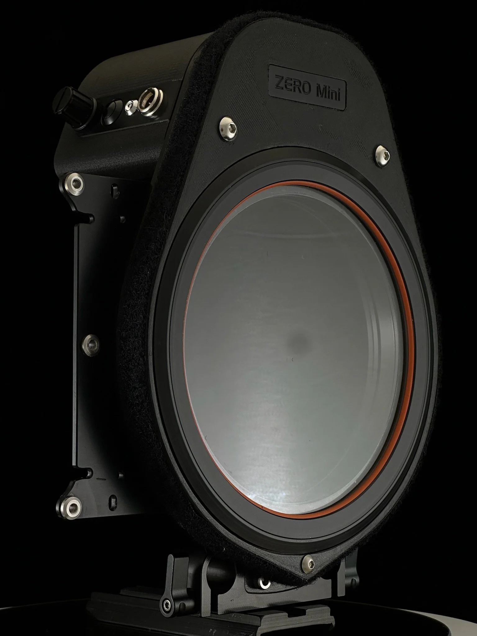 A speaker labeled Zero Mini with a black casing and a large silver speaker cone, set against a black background.