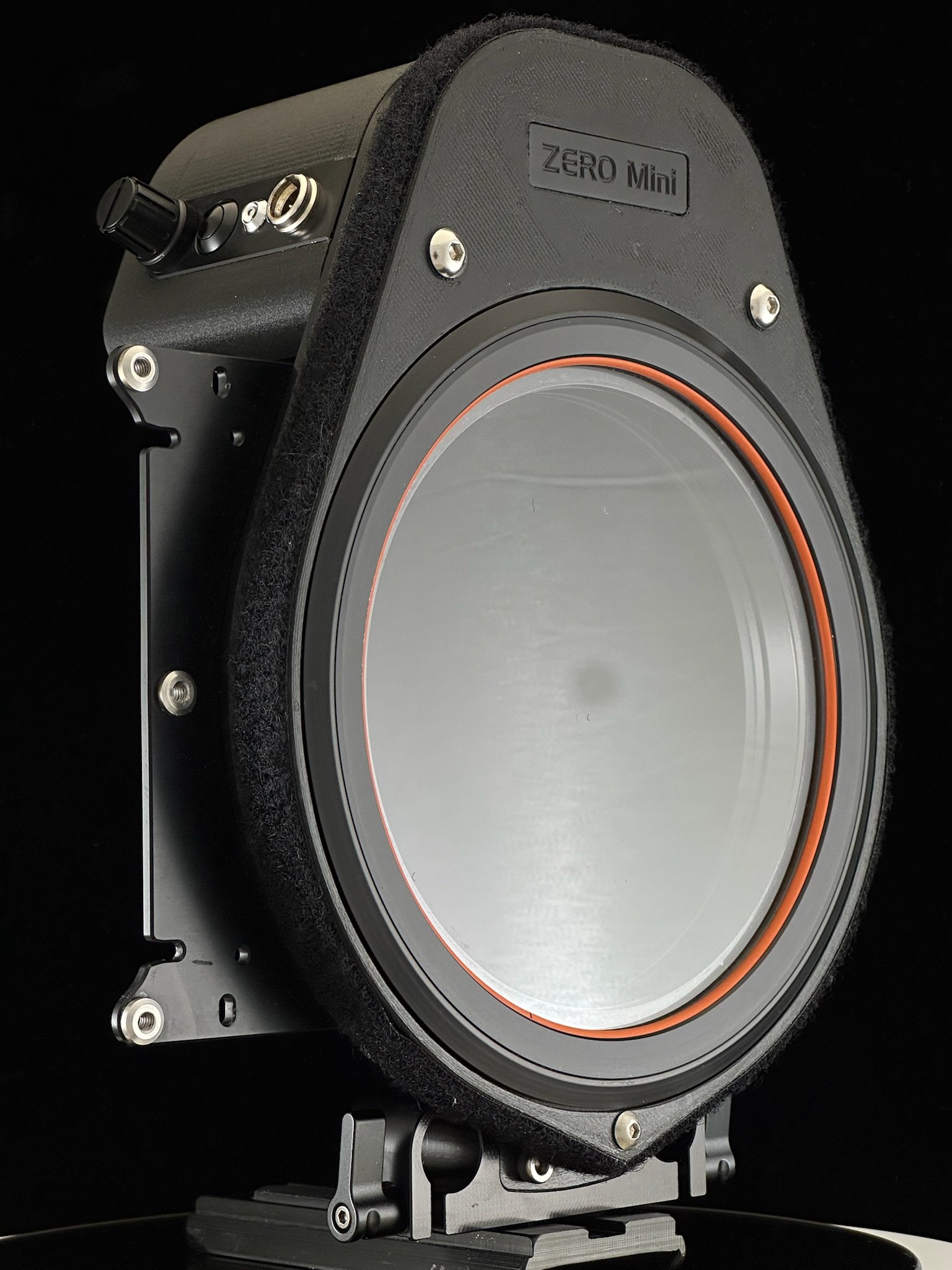 A near-field studio monitor speaker labeled 'ZERO Mini' with a black enclosure, large silver woofer, and various control knobs on the top, set against a black background.
