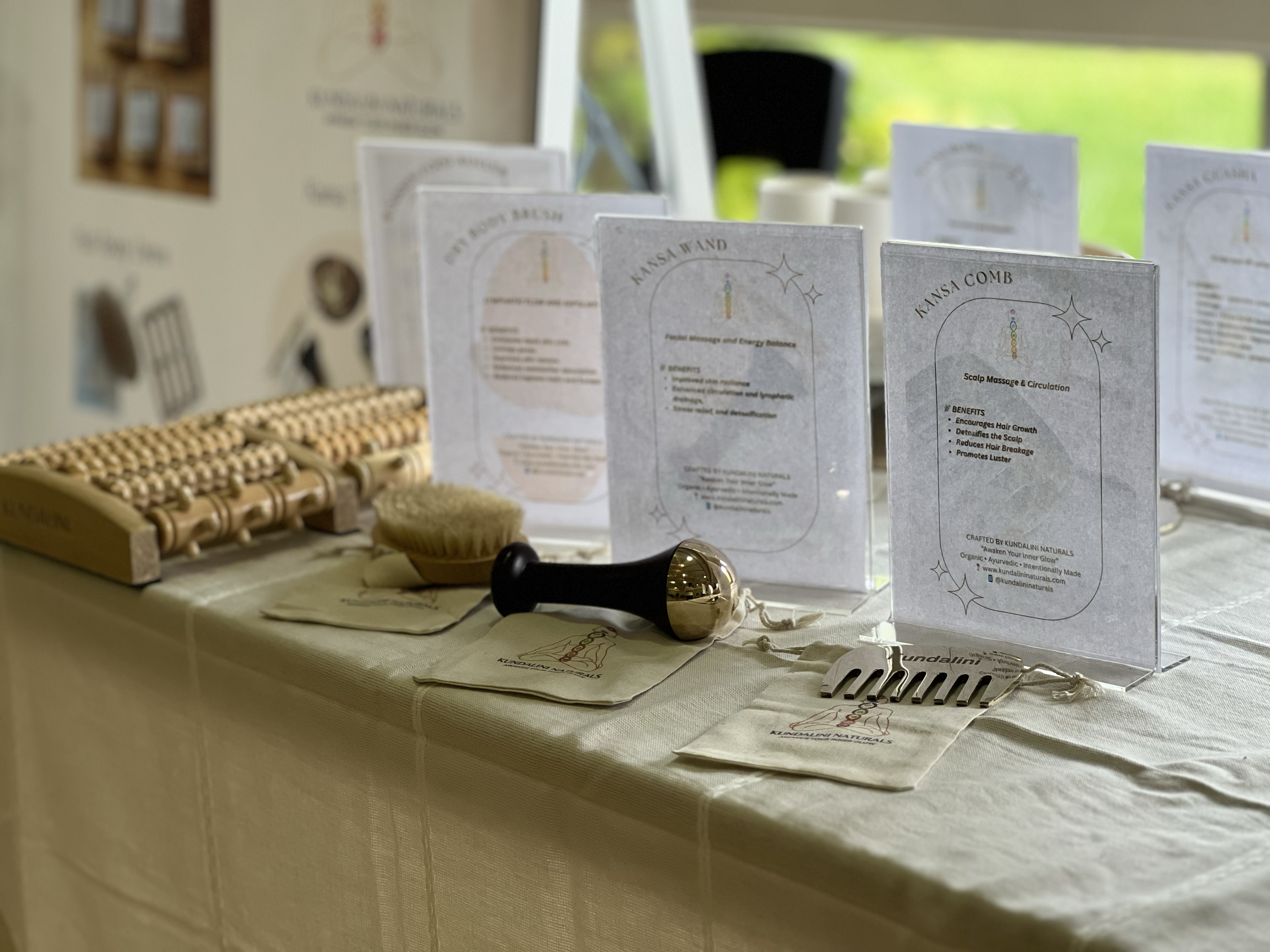 Display table with scalp massage tools, pamphlets about scalp massage benefits, and educational signs at a wellness event.