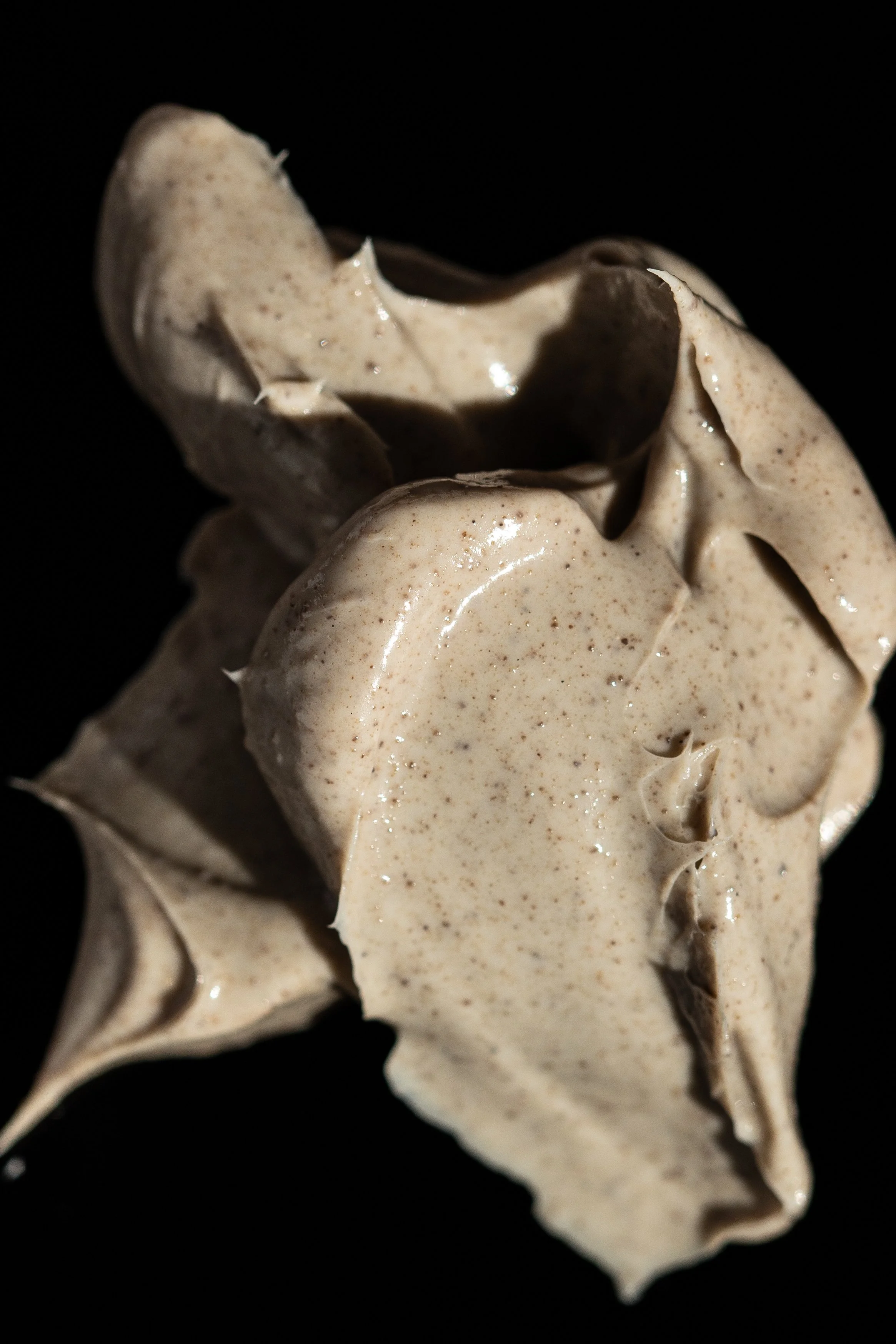 Close-up of a crumpled piece of beige paper or fabric against a black background.