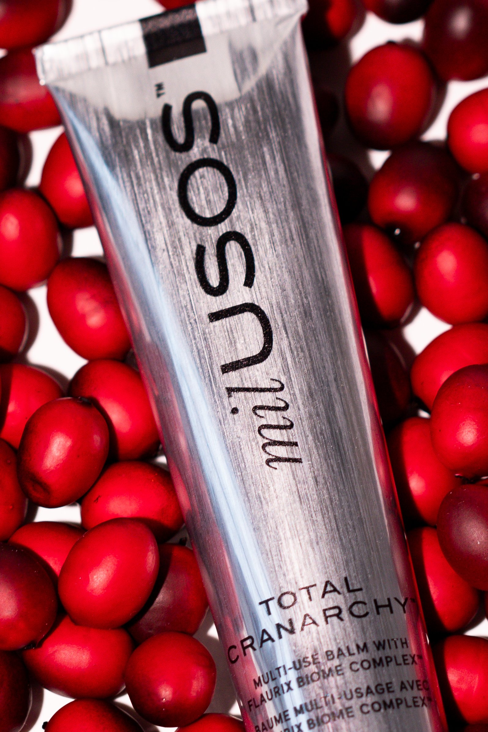 A silver department of defense tube labeled 'In SOSU' surrounded by fresh red cranberries.