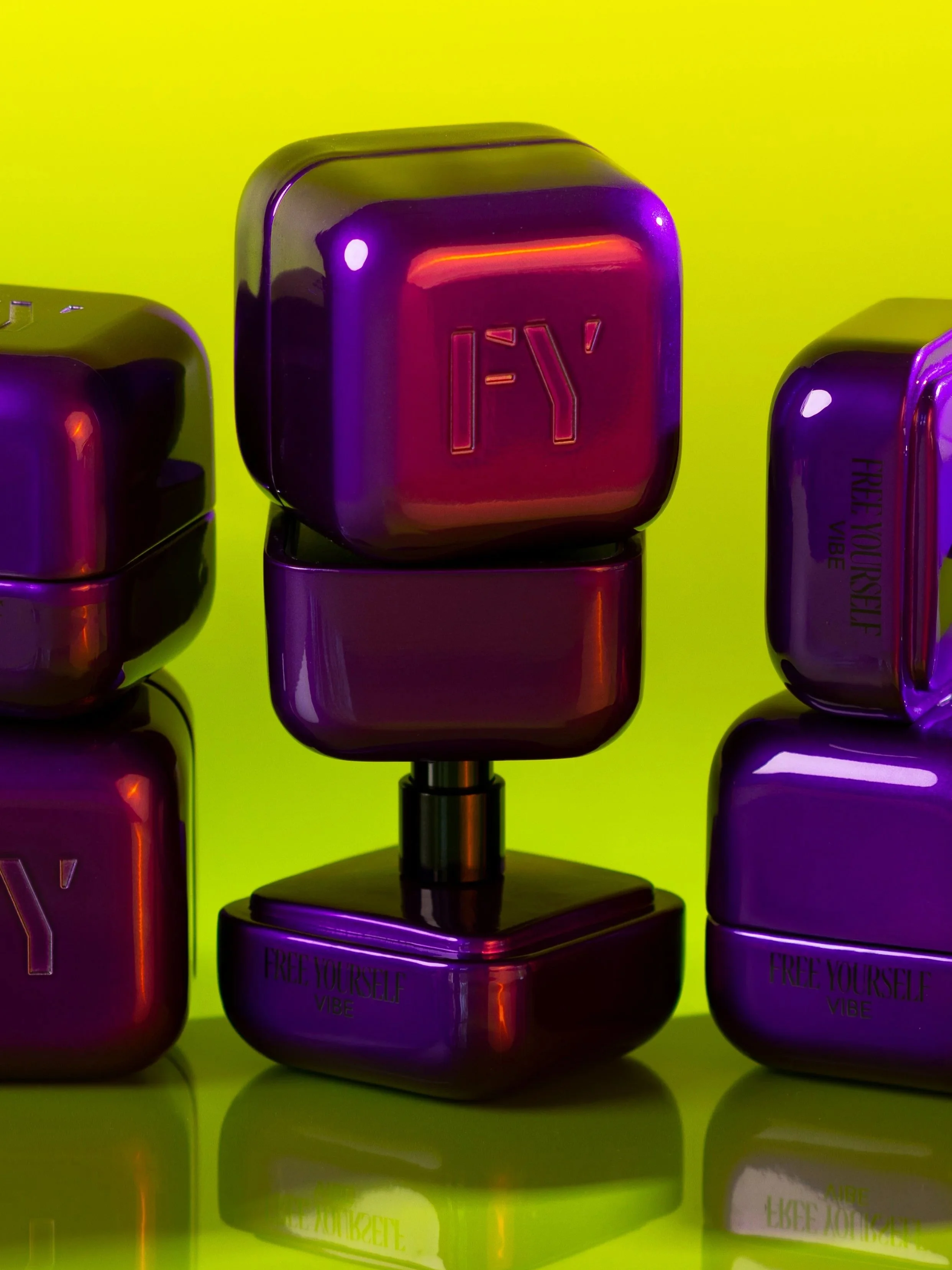 Set of purple cosmetic containers, with one standing on a black base, against a bright yellow background.