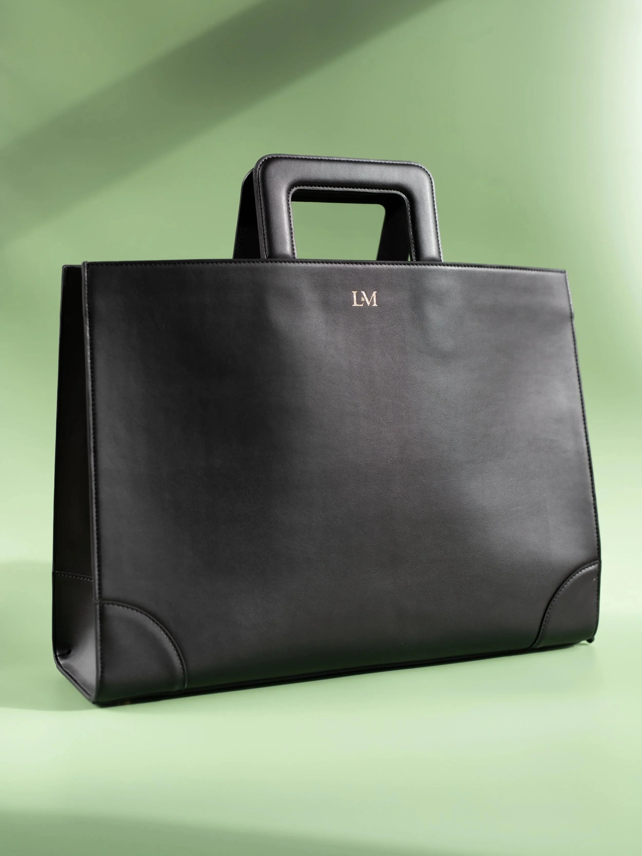 A black leather briefcase with gold initials 'LVM' on a green background.