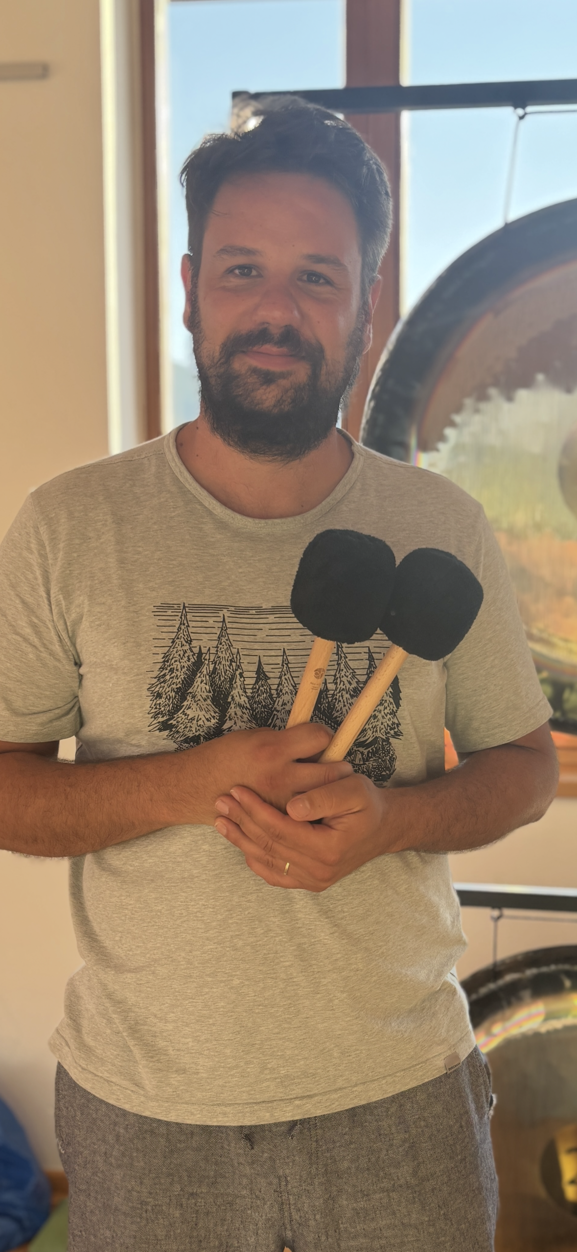 Thomas Feichter, der Gongspieler steht vor seinen Gongs mit zwei Schlägel in der Hand. Es handelt sich um ein Profilbild.