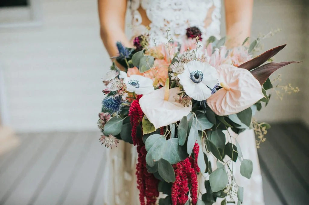 A bridal bouquet with various flowers and greenery, including anemones, eucalyptus, and other blooms.