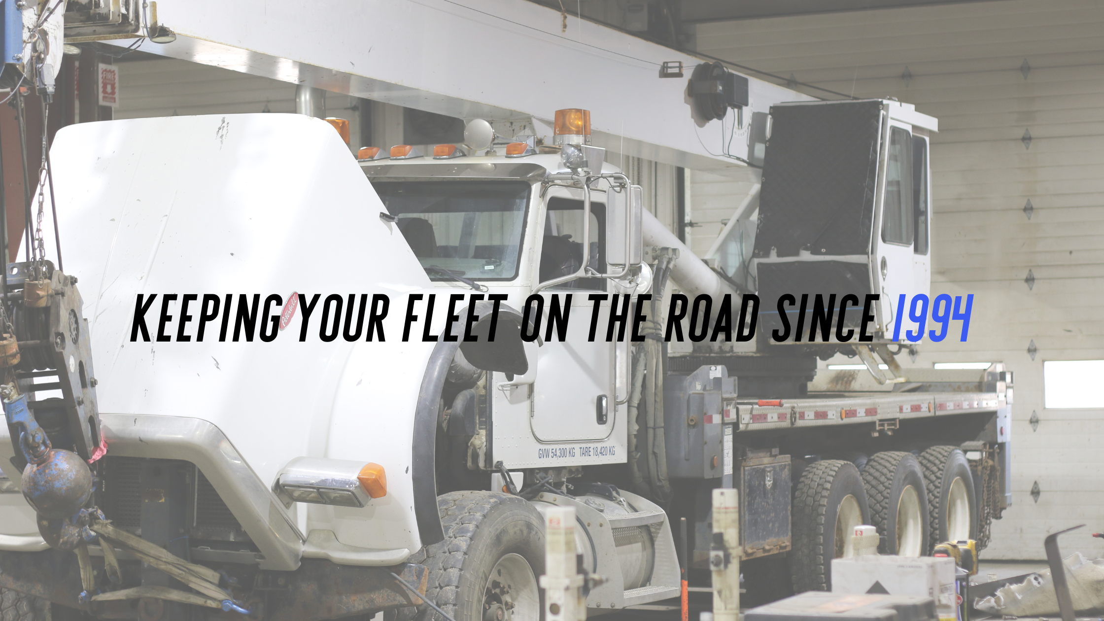A white graffiti cleaning truck with text overlay: "Keeping your fleet on the road since 1994" in black, italicized, and blue fonts, inside an industrial garage.