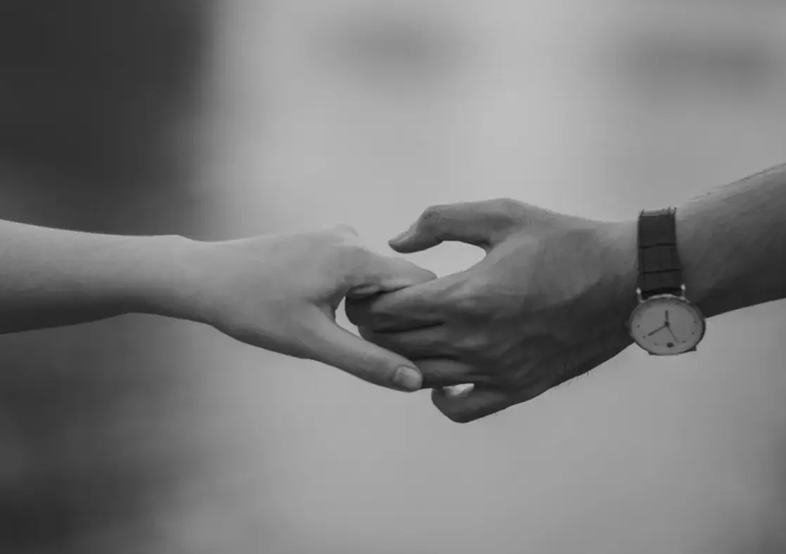 Close-up black-and-white image of two hands holding gently - Liminality Professional Psychotherapist.webp