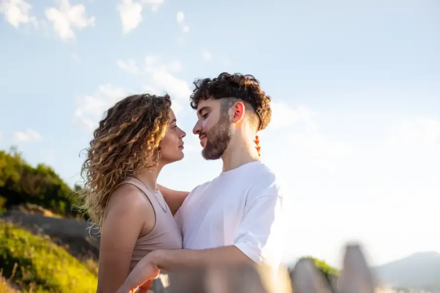 A couple embraces affectionately in front of a wooden fence, showcasing their love and connection.