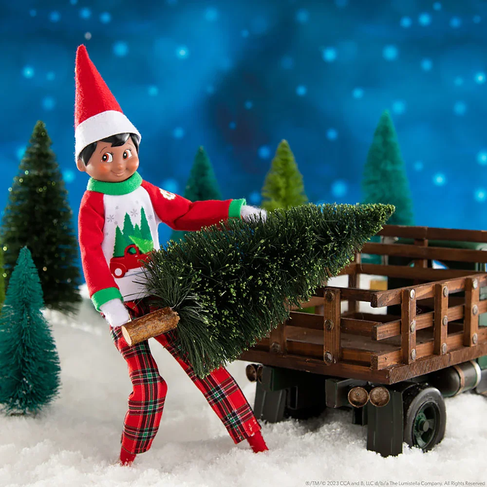 Mischievous Christmas elf named Nordmann carrying a small Christmas tree on a wagon among U-Cut trees at Buckendorf Family Tree Farm.