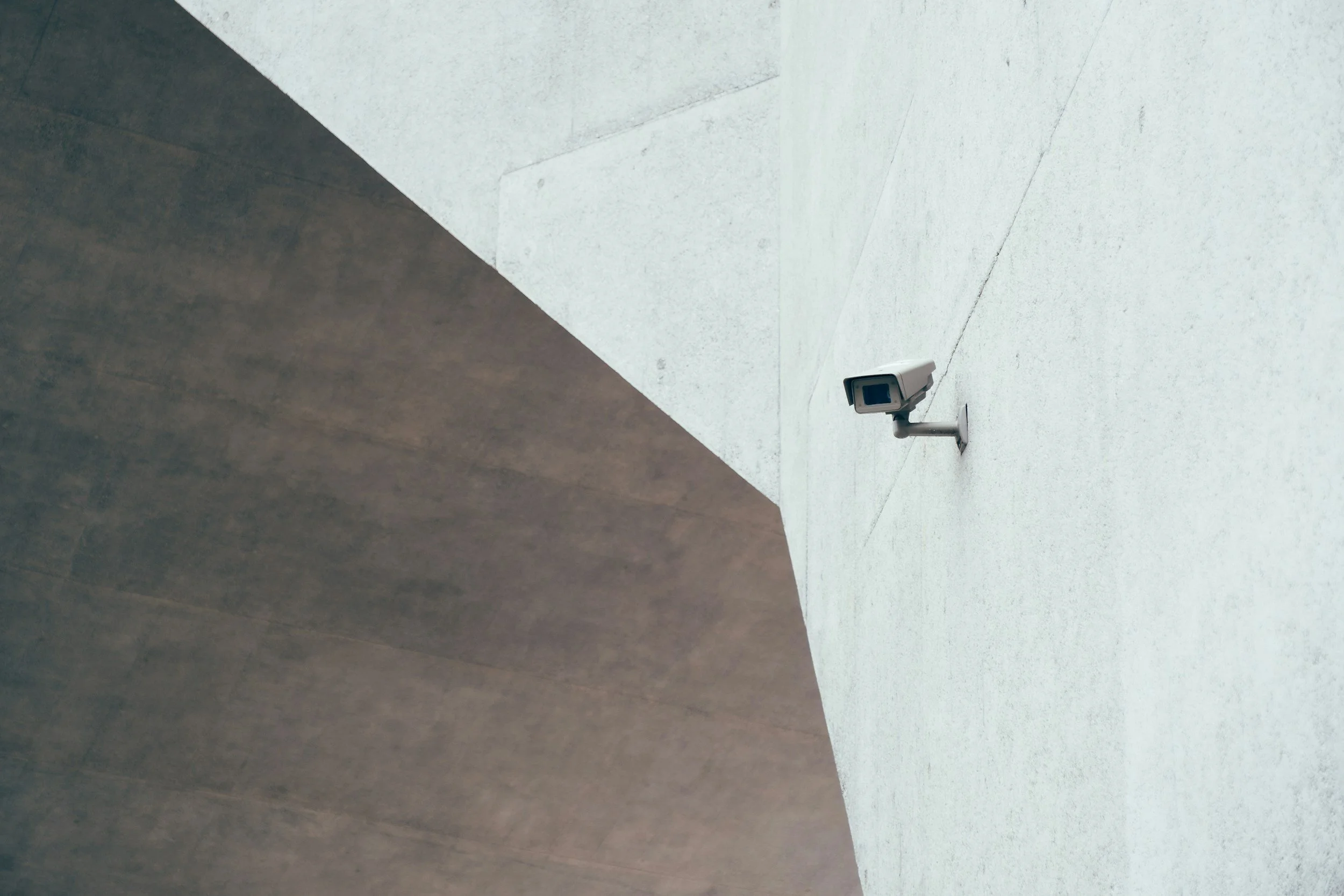 Security camera mounted on a white concrete wall.