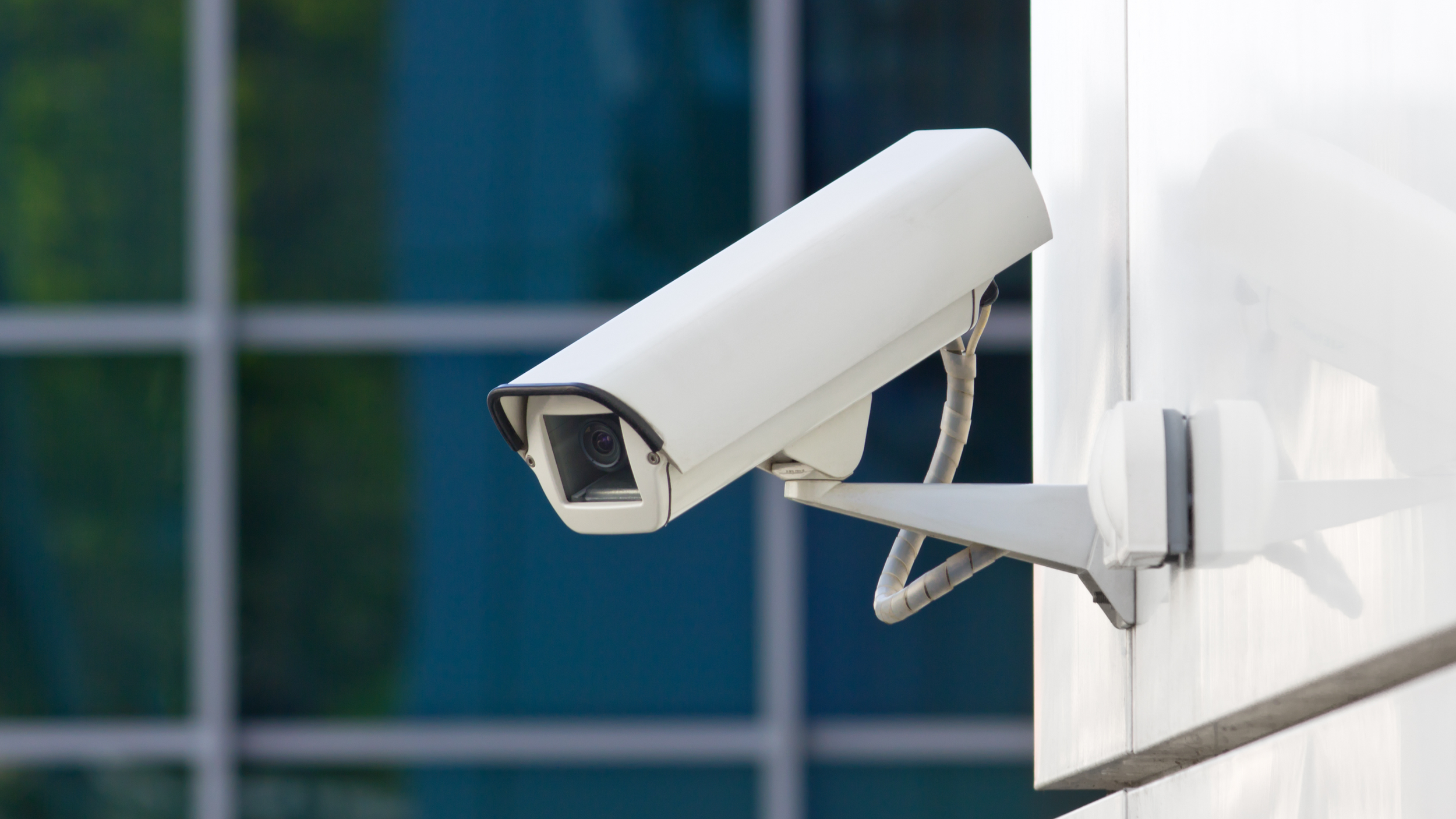 Close-up of a white security camera mounted on the exterior of a building.