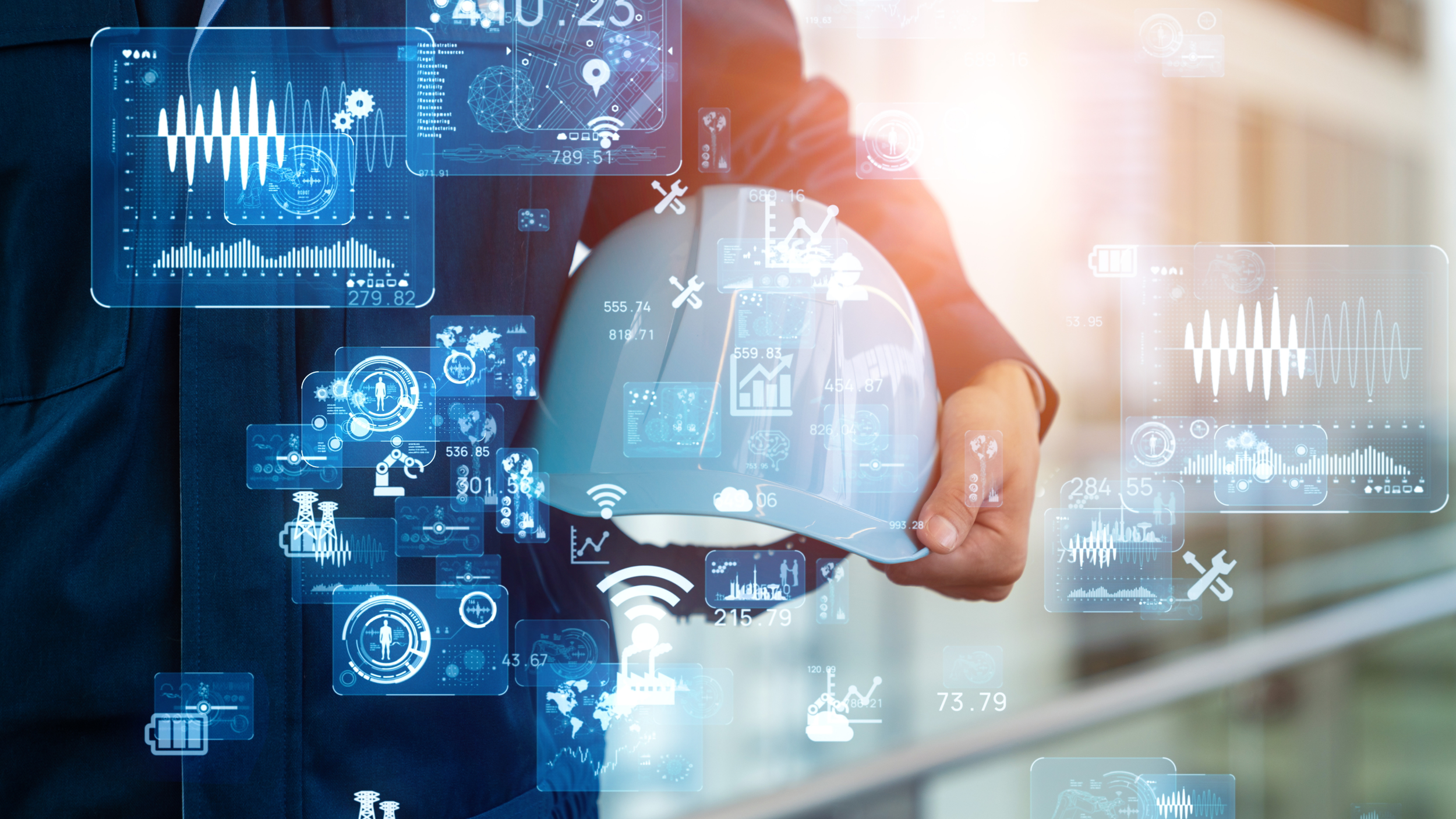 A person in business attire holding a construction helmet, with virtual digital data, charts, icons, and graphs projected around, representing technology and innovation in engineering or construction.