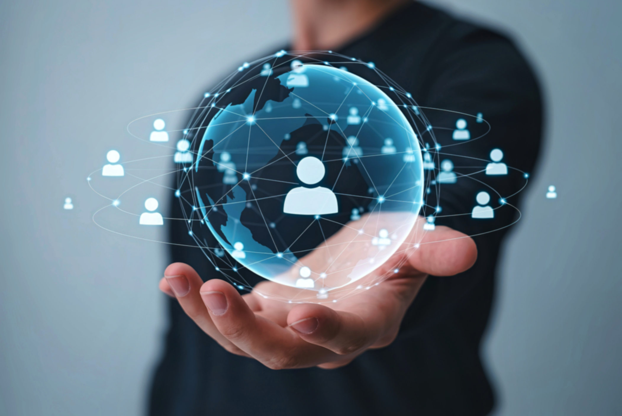 Person holding out their hand with a digital globe and network of connected human icons representing global online communication and social connectivity.