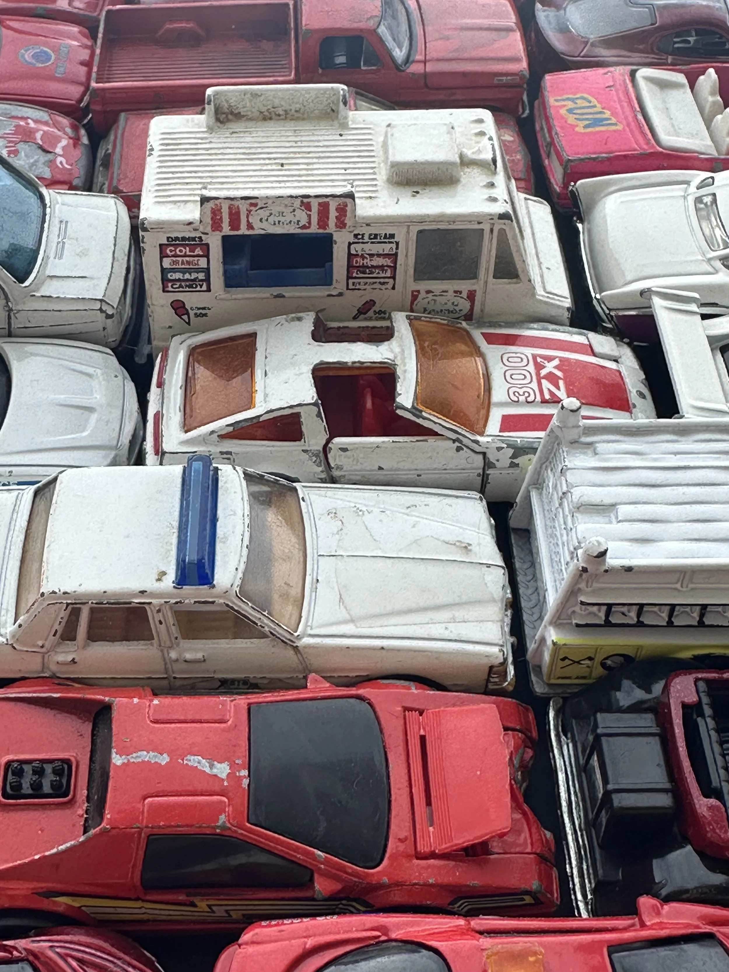 Array of vintage toy cars in various colors and models, with some showing signs of wear and tear.