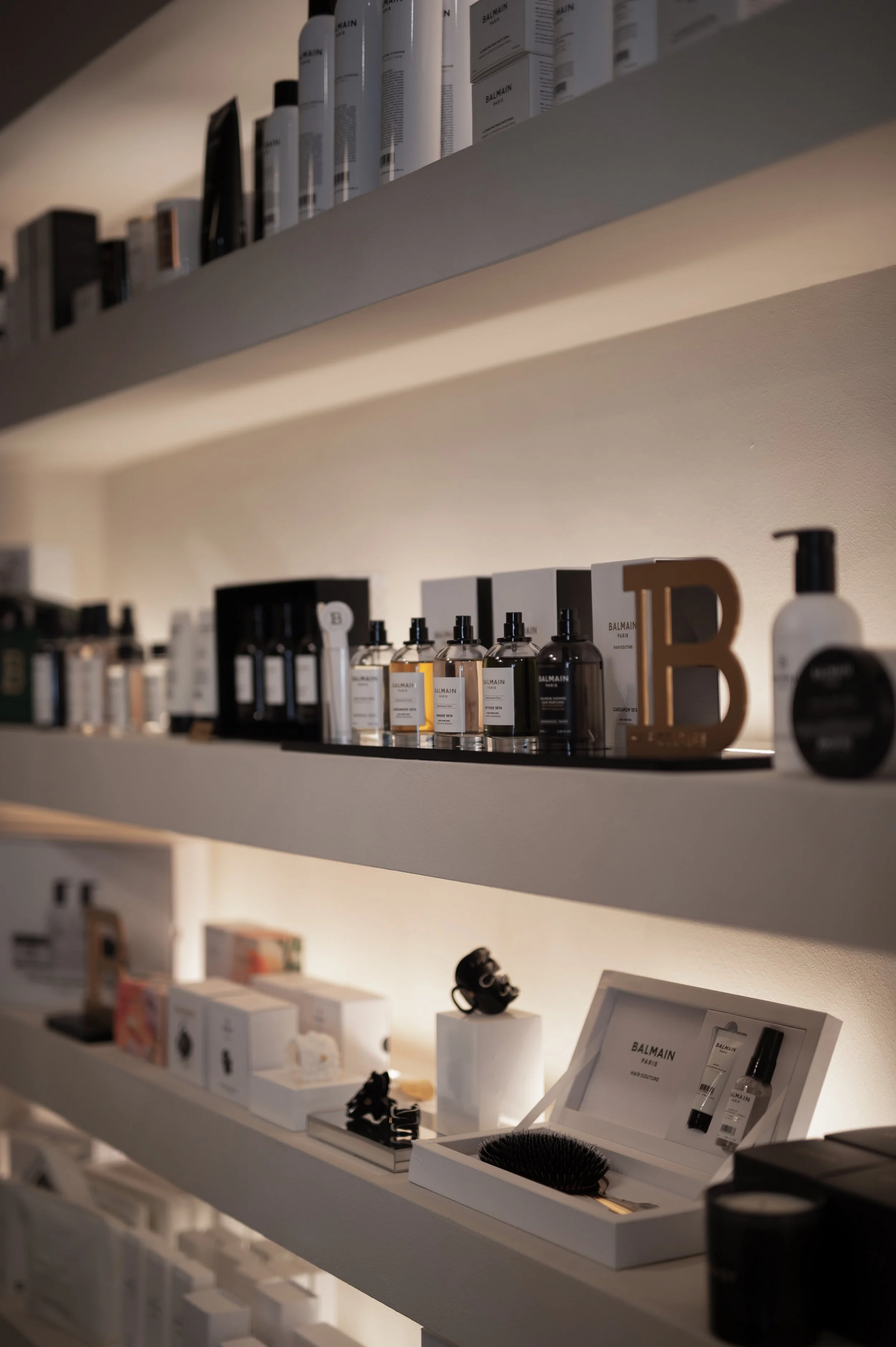 Display of skincare and beauty products on white shelves, including bottles, boxes, and grooming tools.