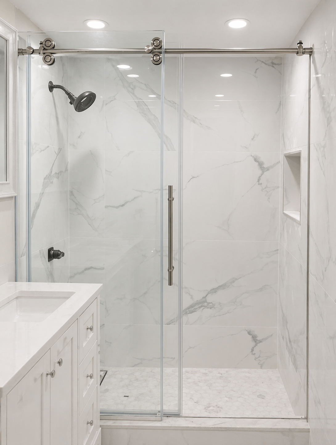 Modern shower with marble tiles, a sliding glass door, a shower head, a built-in wall niche, and a white vanity with a sink.