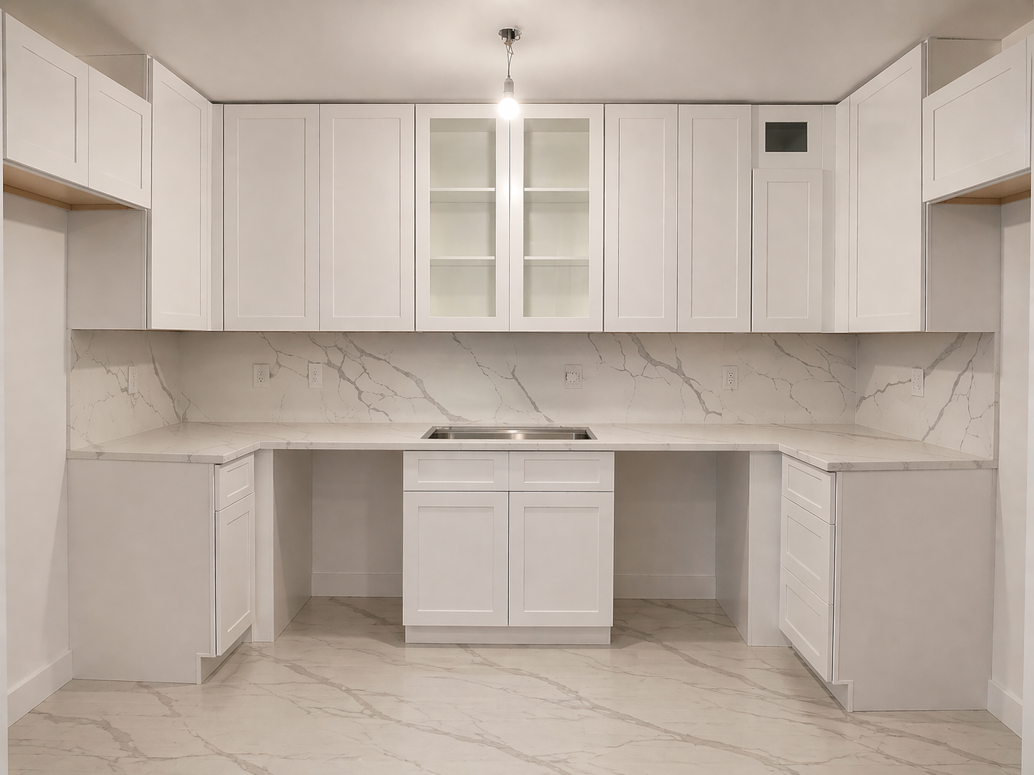 Modern white kitchen with marble countertops and backsplash, upper cabinets with glass doors, and an under-mount sink