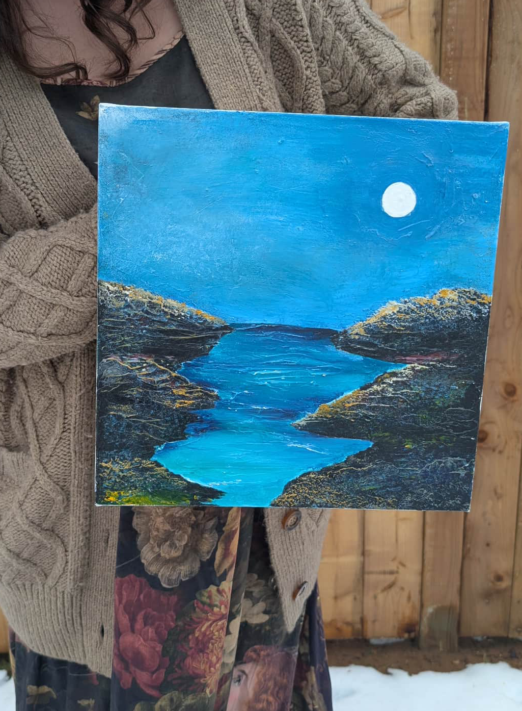 Painting of a lake at night with a full moon in the sky, framed by rocky cliffs.