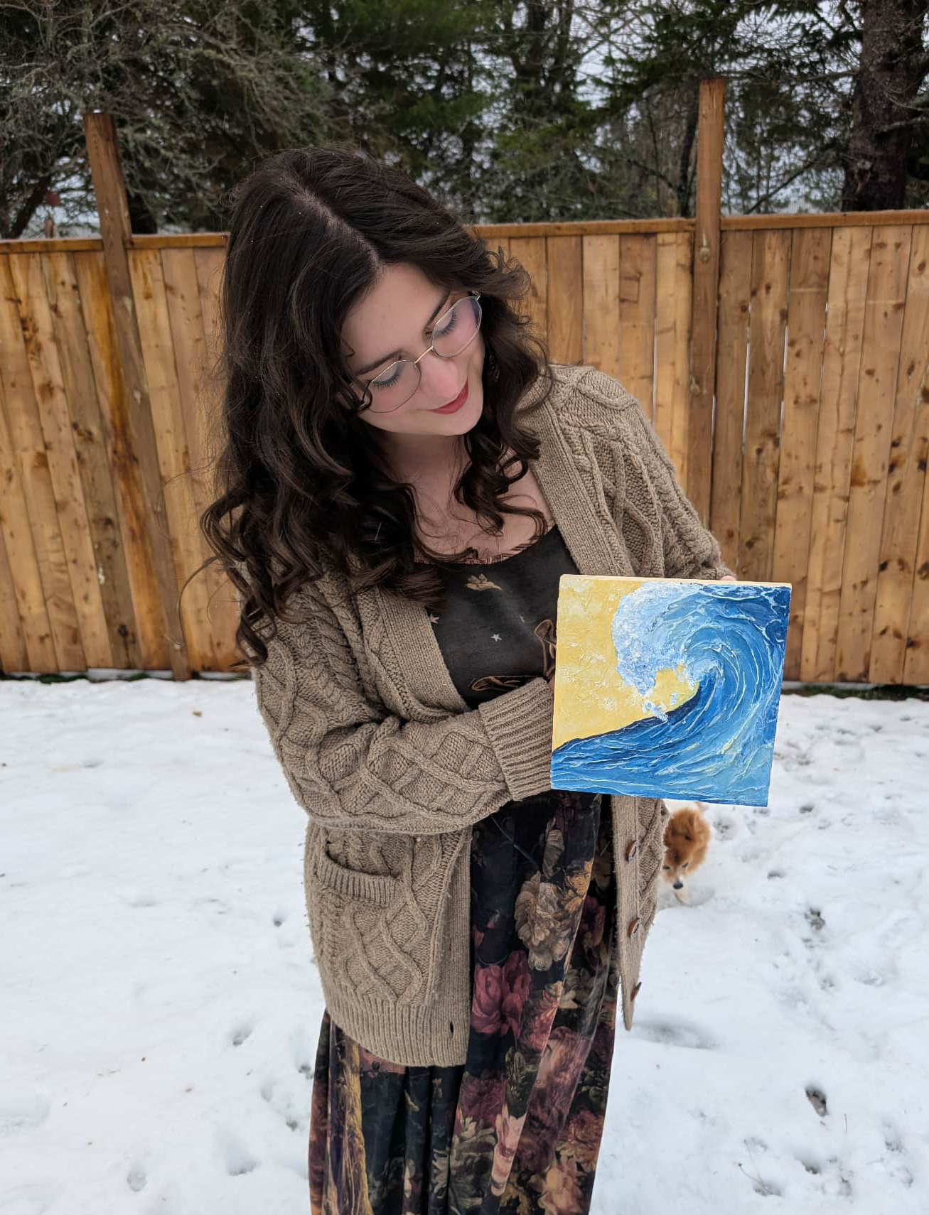 Women holding painting of a wave outside in the winter