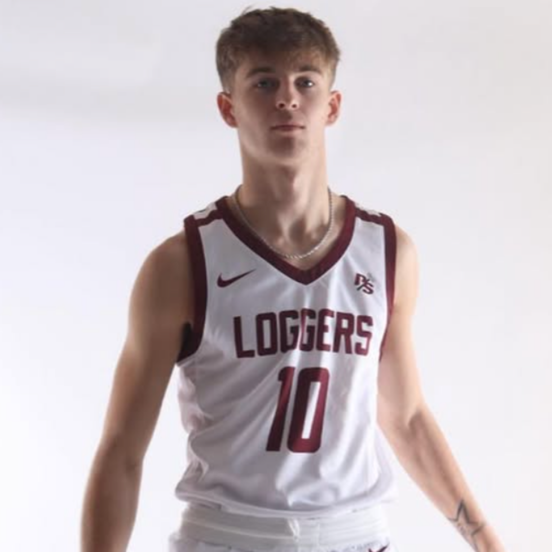 Young male volleyball player in a white and maroon jersey with the word LOGGERS and the number 10, standing against a plain light background.