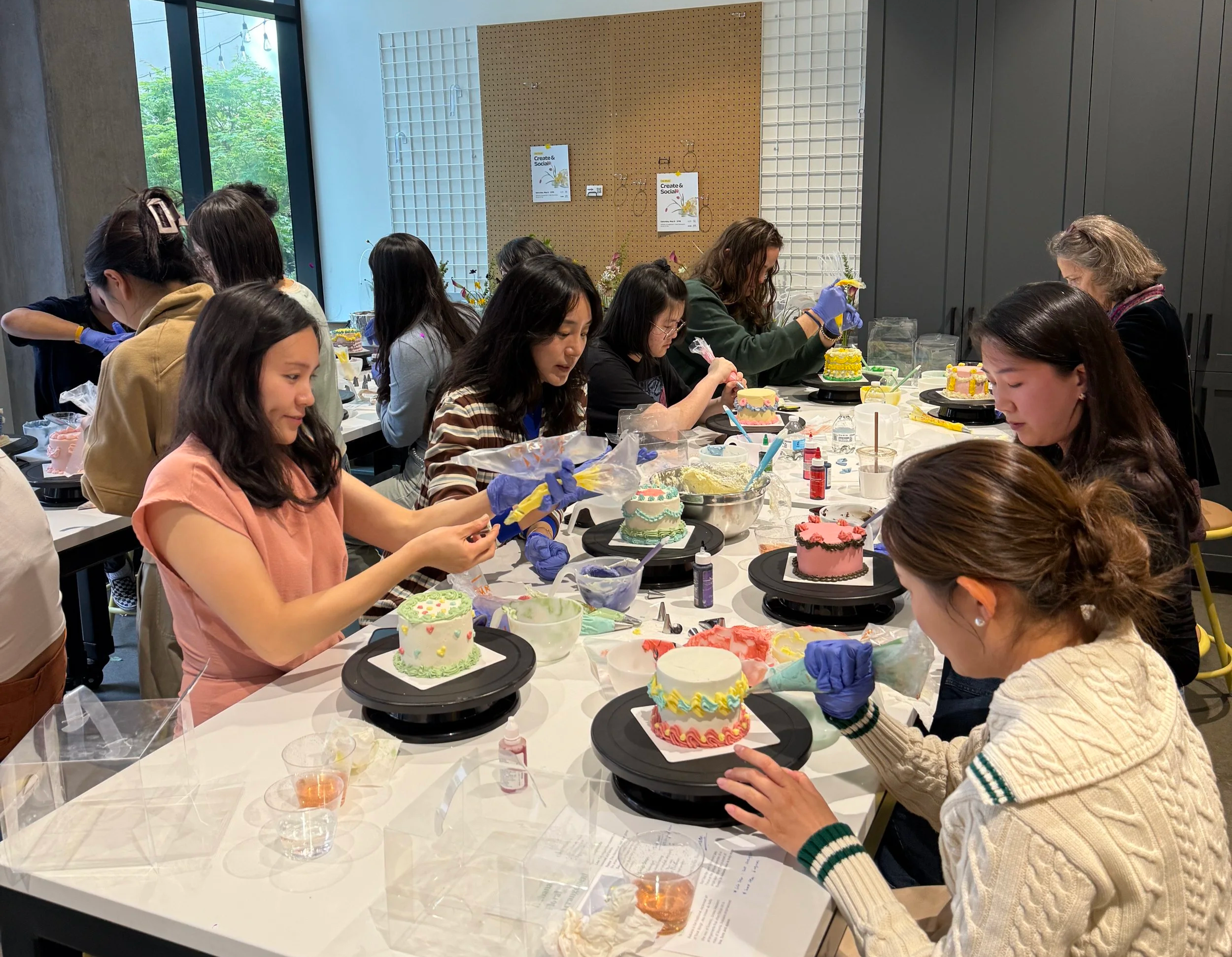 People decorating colorful cakes at a table during a cake decorating workshop.