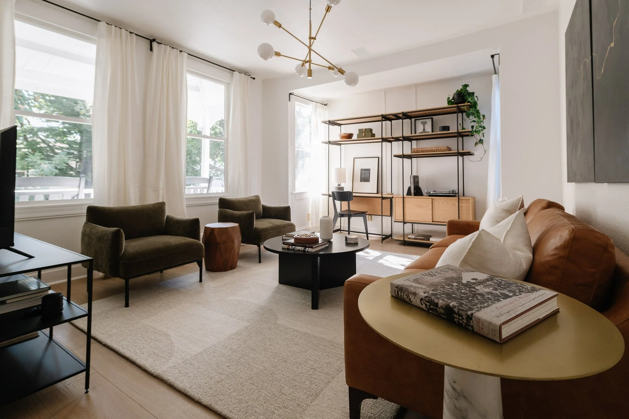 Sunlit parlor with a sofa, armchairs, and large windows
