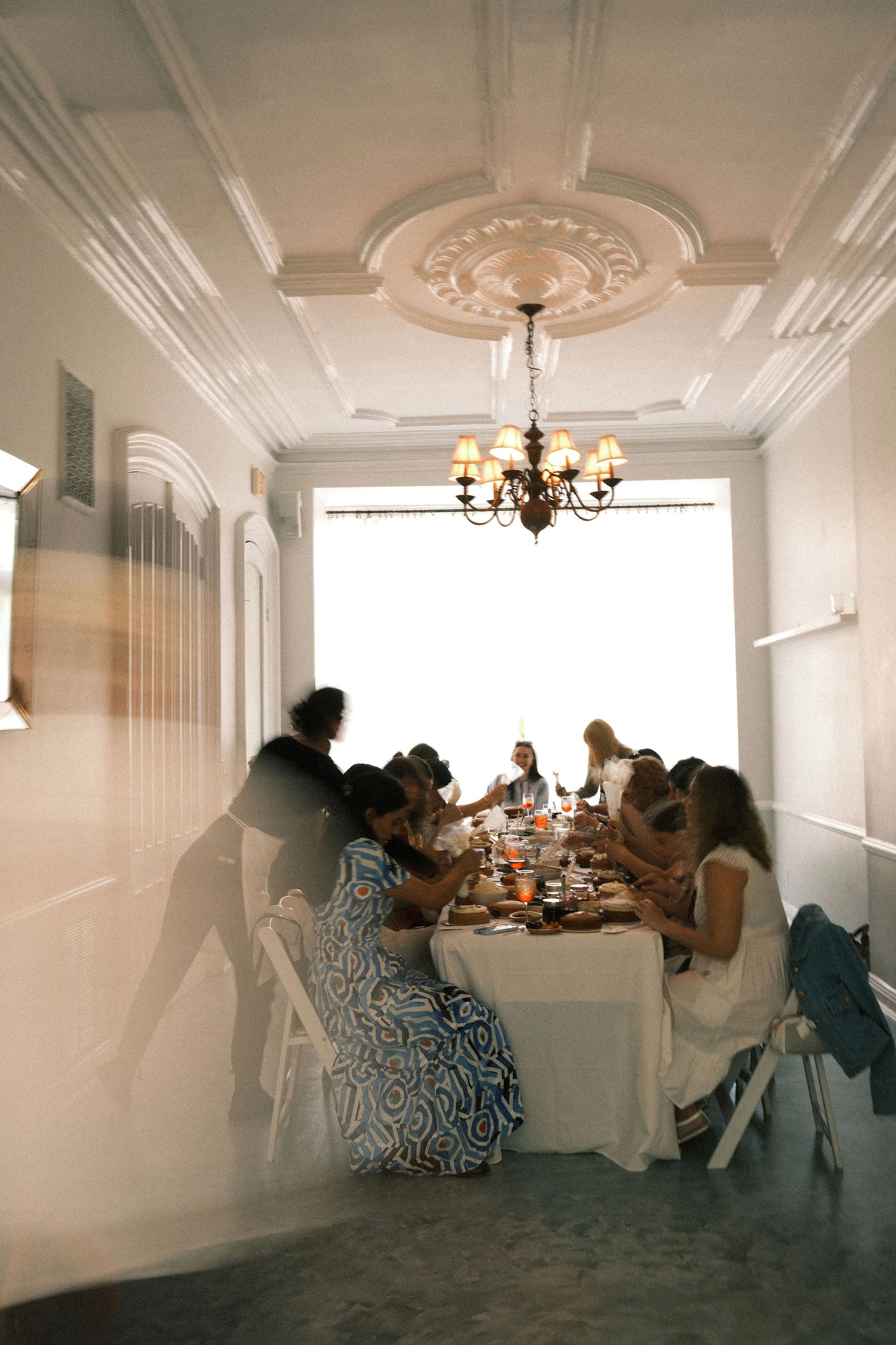 People gathered around a banquet table in a well-lit dining room, enjoying a meal together for an event.