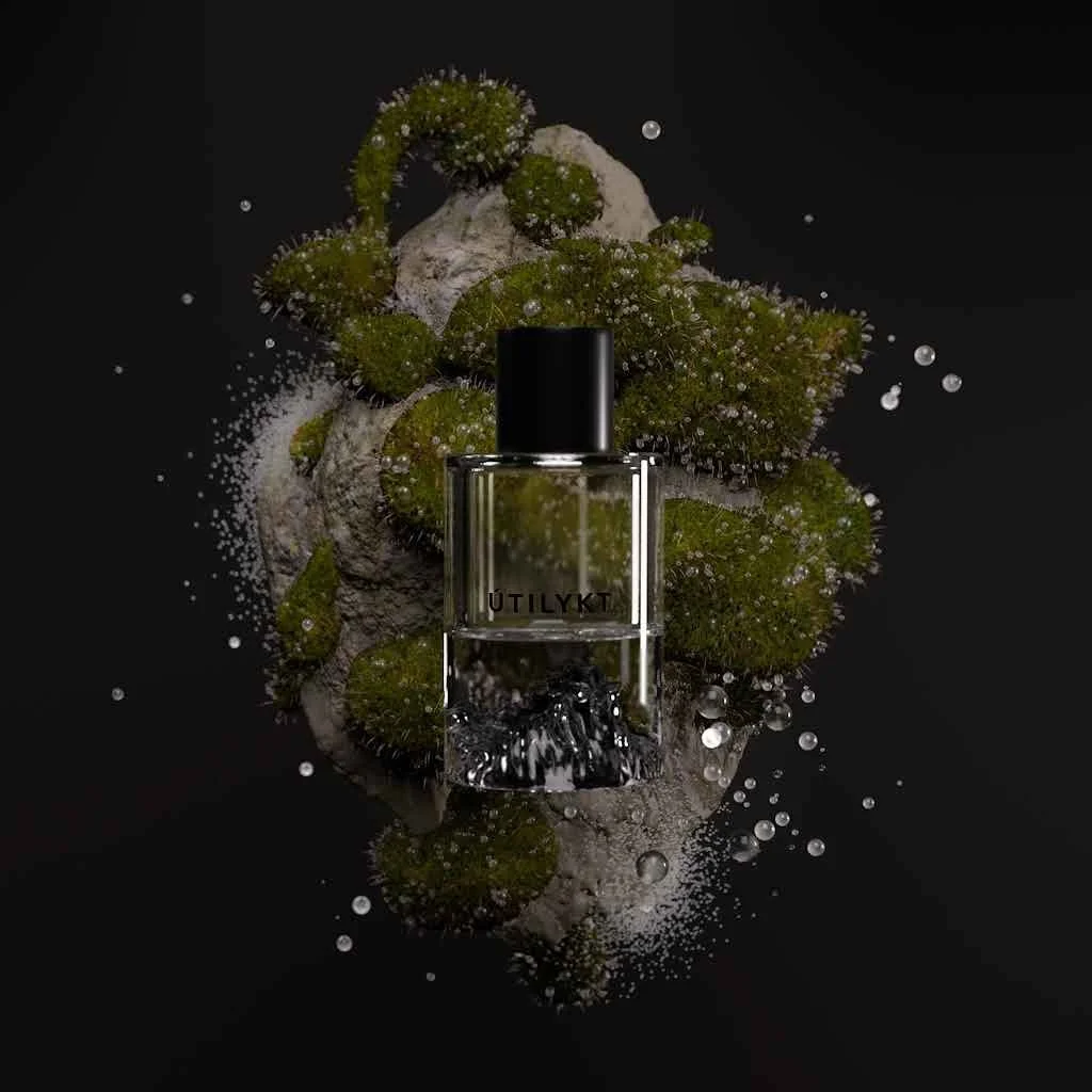 A perfume bottle labeled UMyltk surrounded by rocks and green moss with water droplets on a dark background.