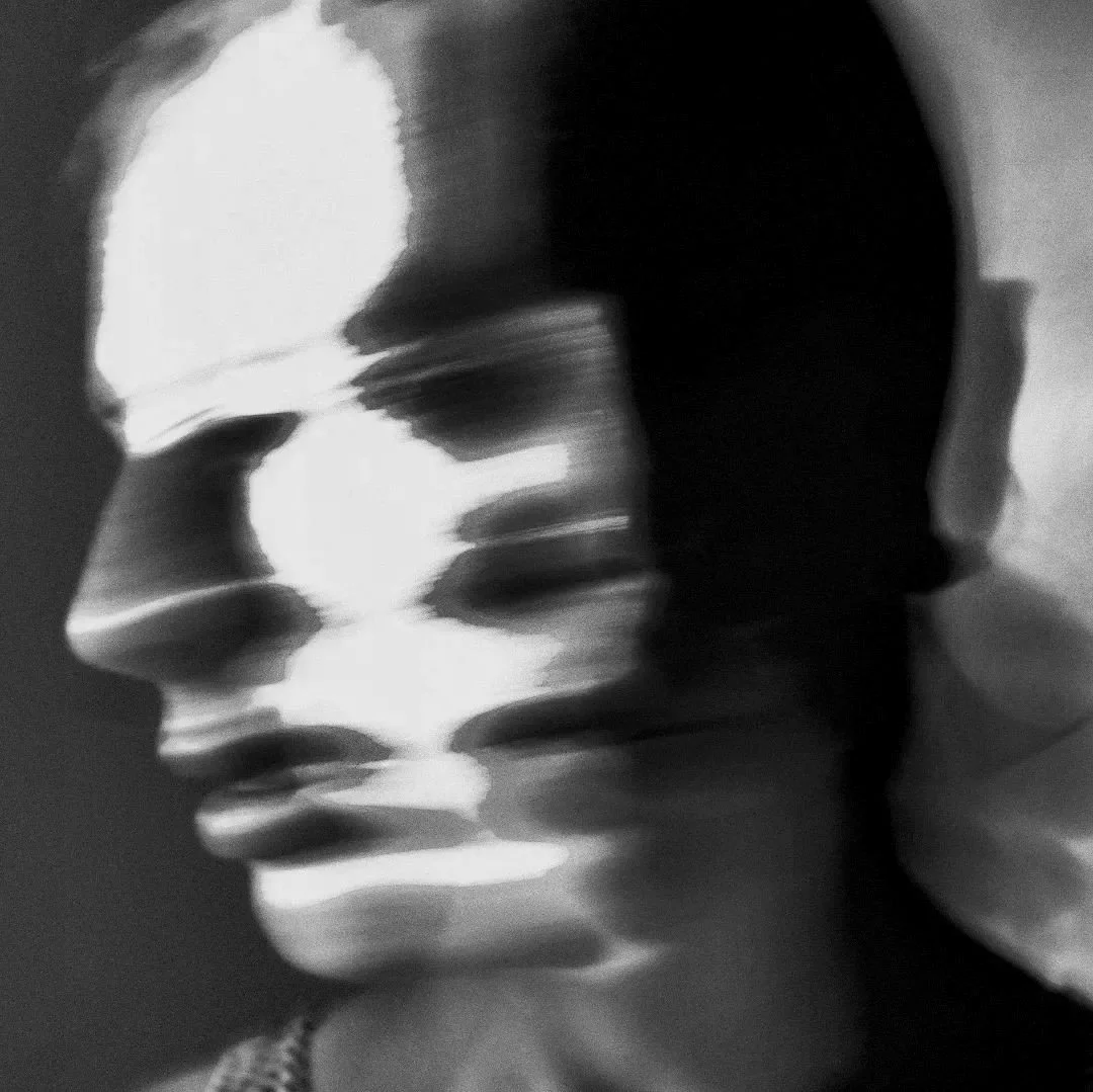 A black and white abstract sculpture of a human face in profile, highlighting facial features.