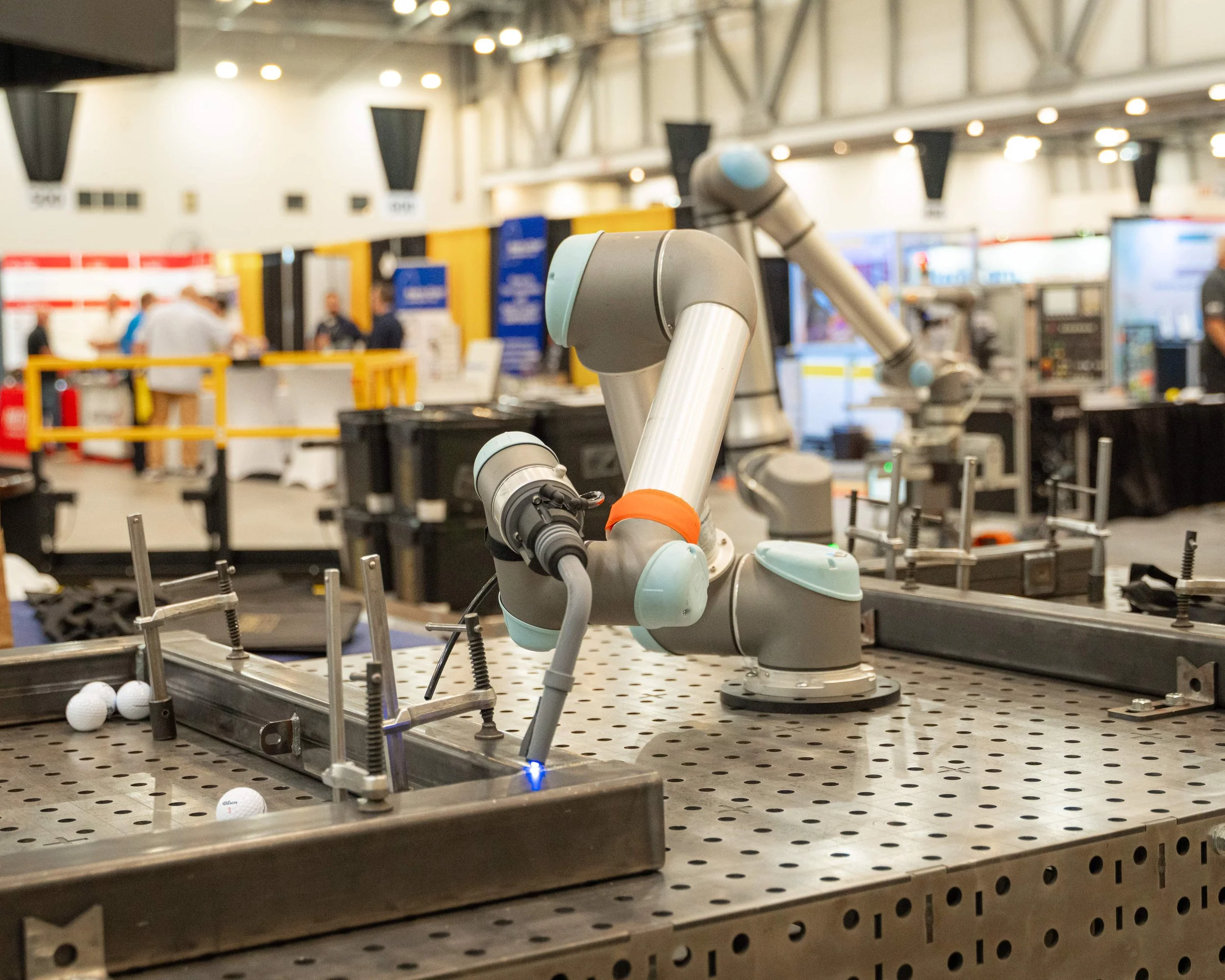 A robotic arm working on a golf ball assembly line at a trade show.