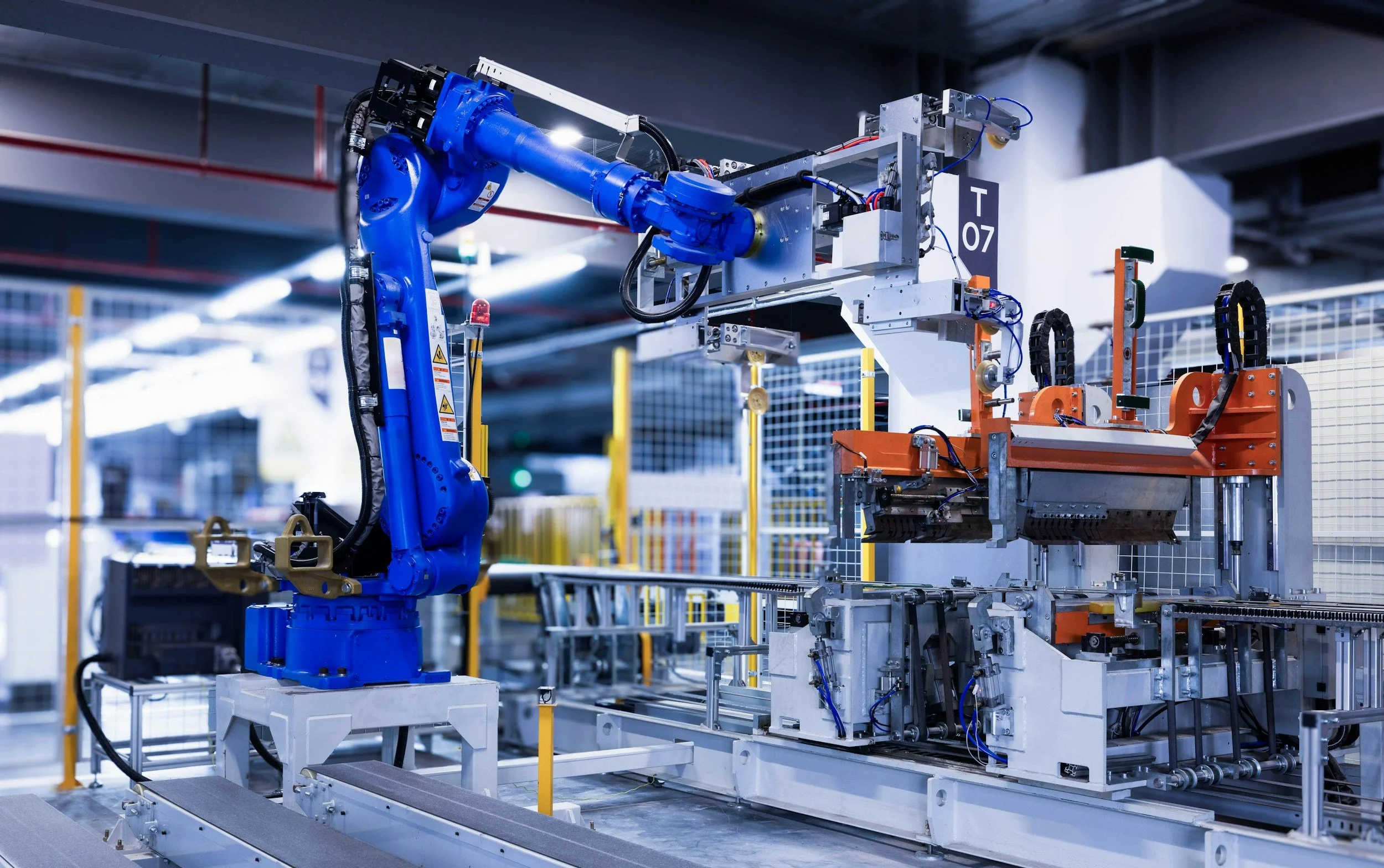 Industrial robotic arm with blue and gray components working on an assembly line in a factory.