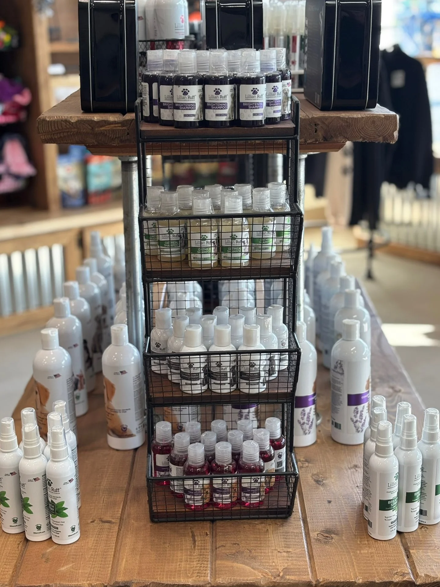 Display of various bottles of shampoo, conditioner, and spray on a wooden table and shelves in a store.