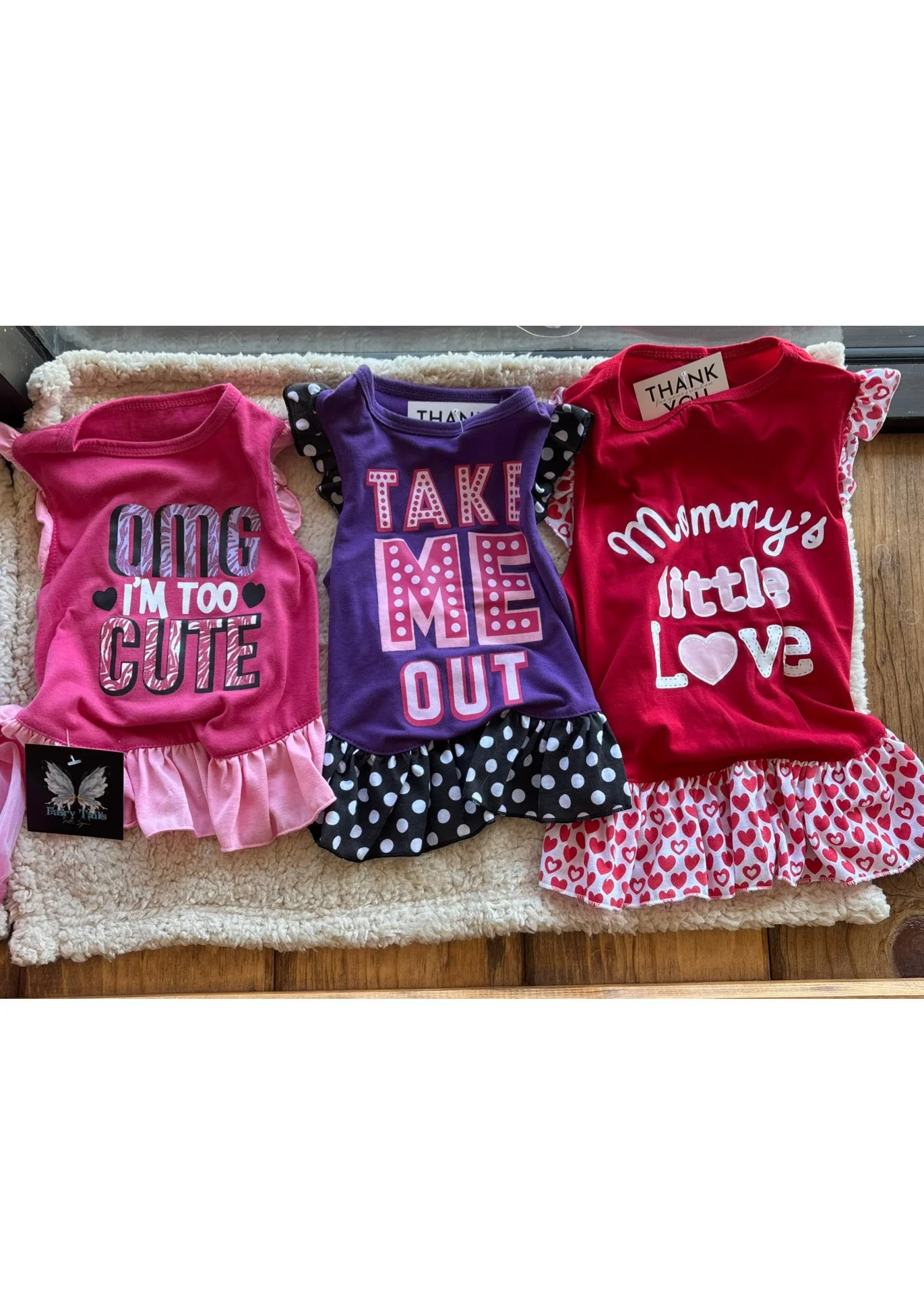 Three colorful children's dresses with playful prints and ruffled hems, laid out on a soft surface.