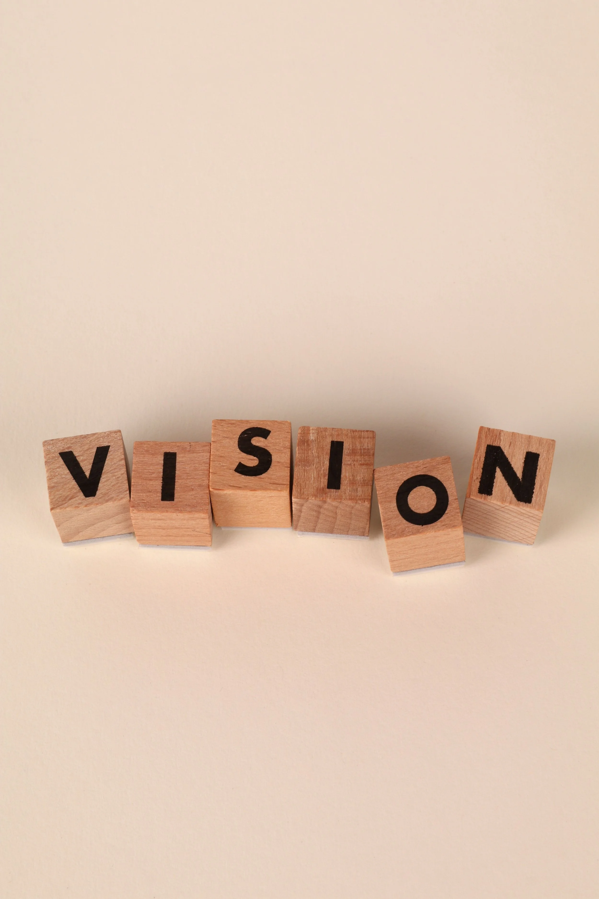 Wooden blocks spelling out the word "VISION" on a light-colored surface.