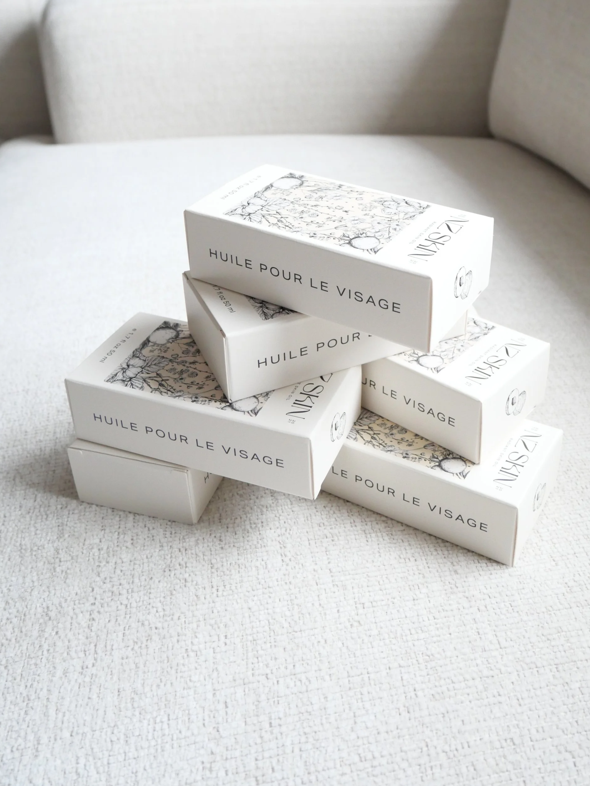 Stack of six white boxes labeled 'NZ SKIN' on a light textured surface.