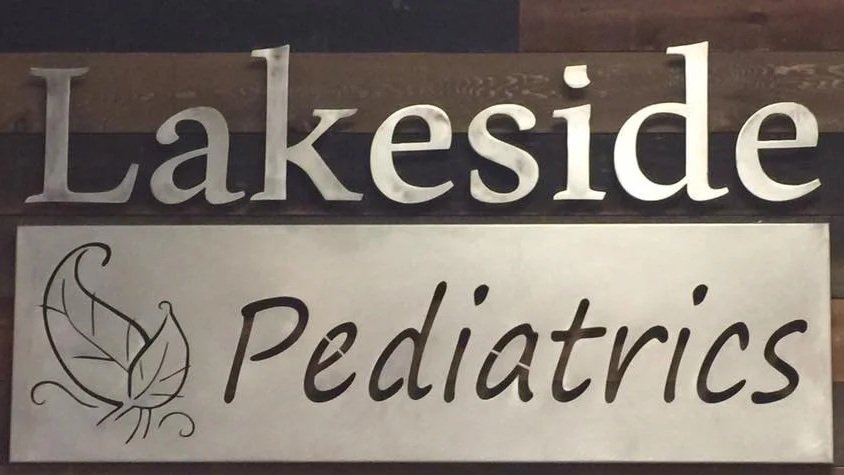 Sign with the words "Lakeside Pediatrics" and a leaf logo on a wooden background.