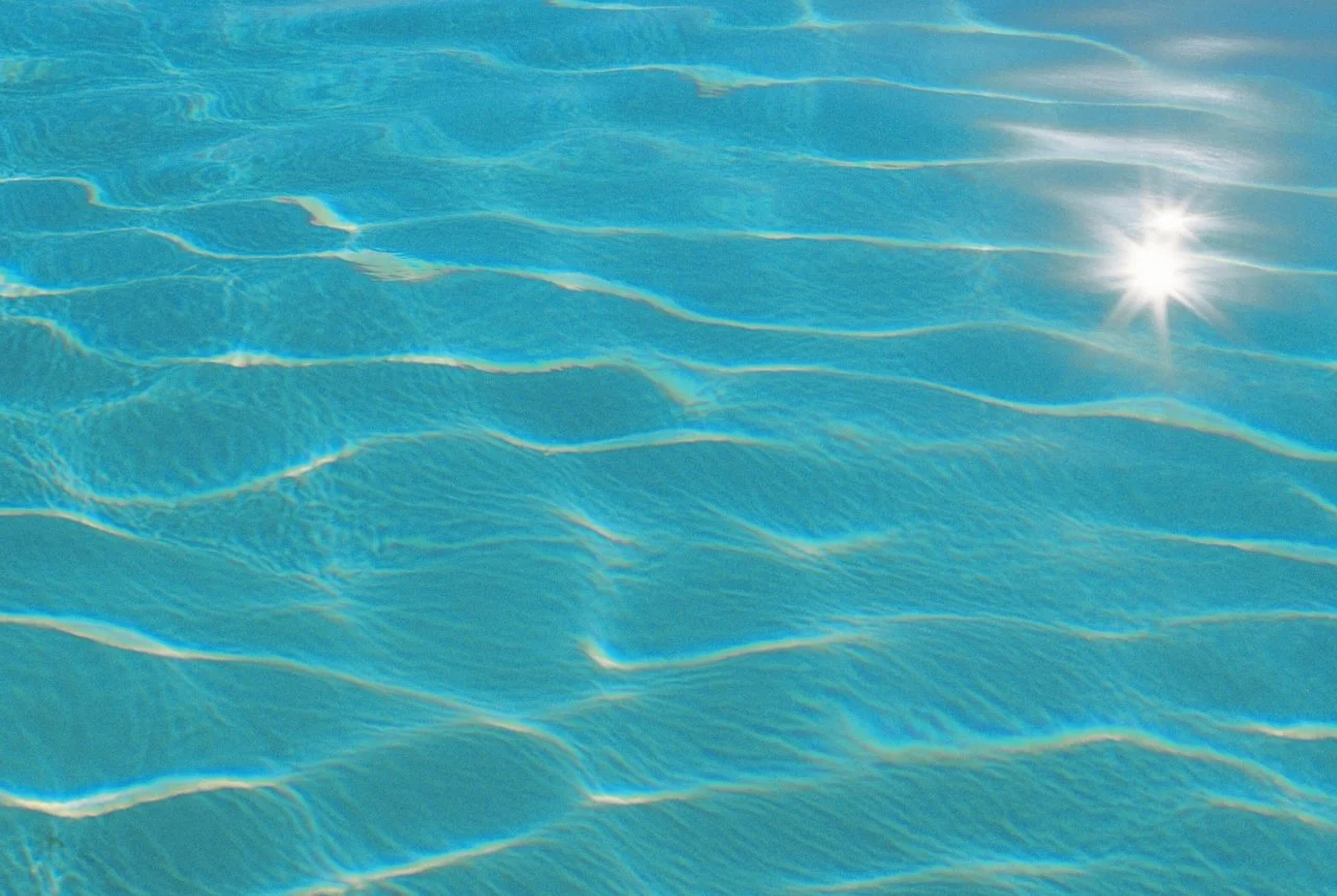 Sparkling sunlight reflecting on the rippling surface of a swimming pool.