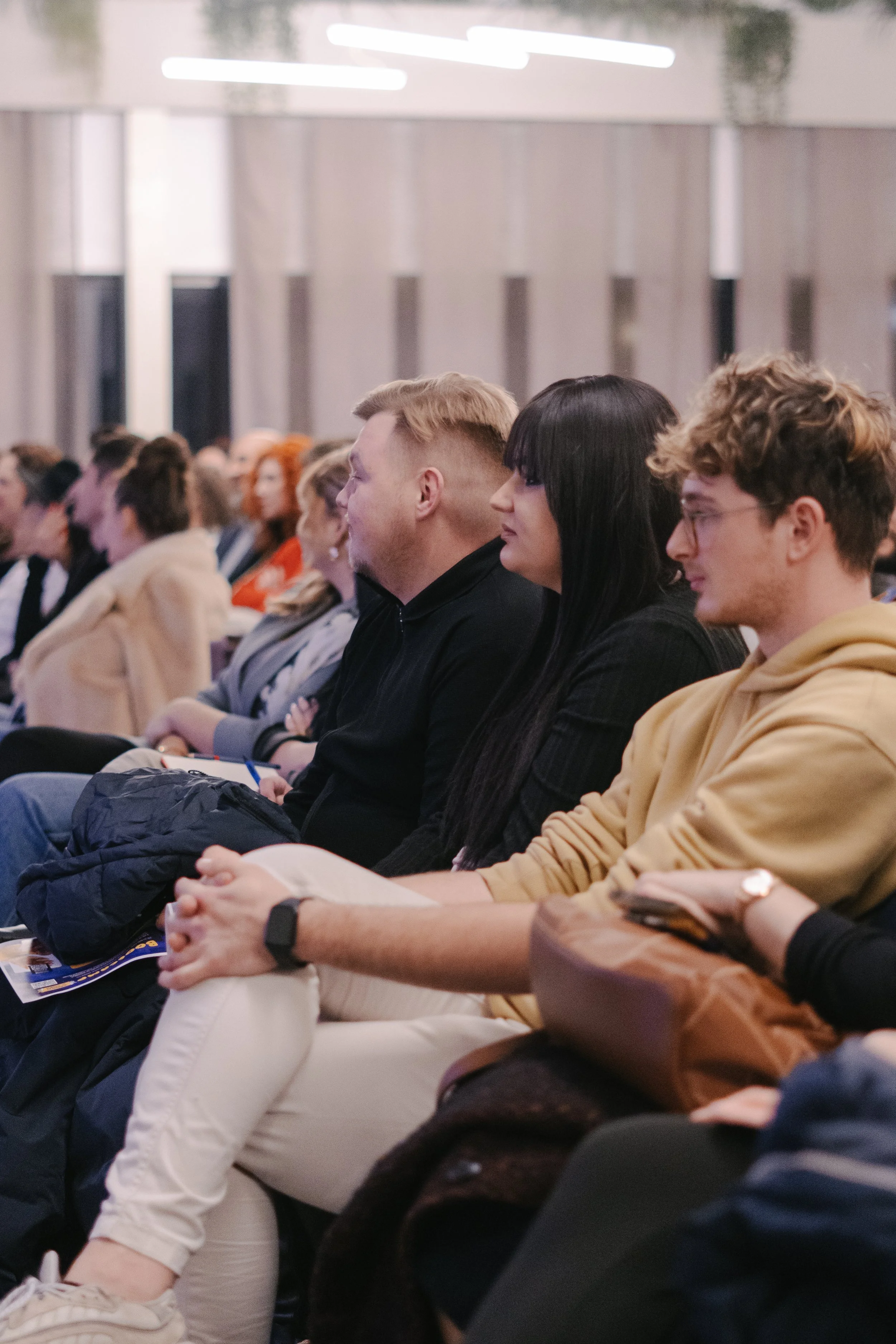 People seated and attending a conference or seminar in a room with modern decor.