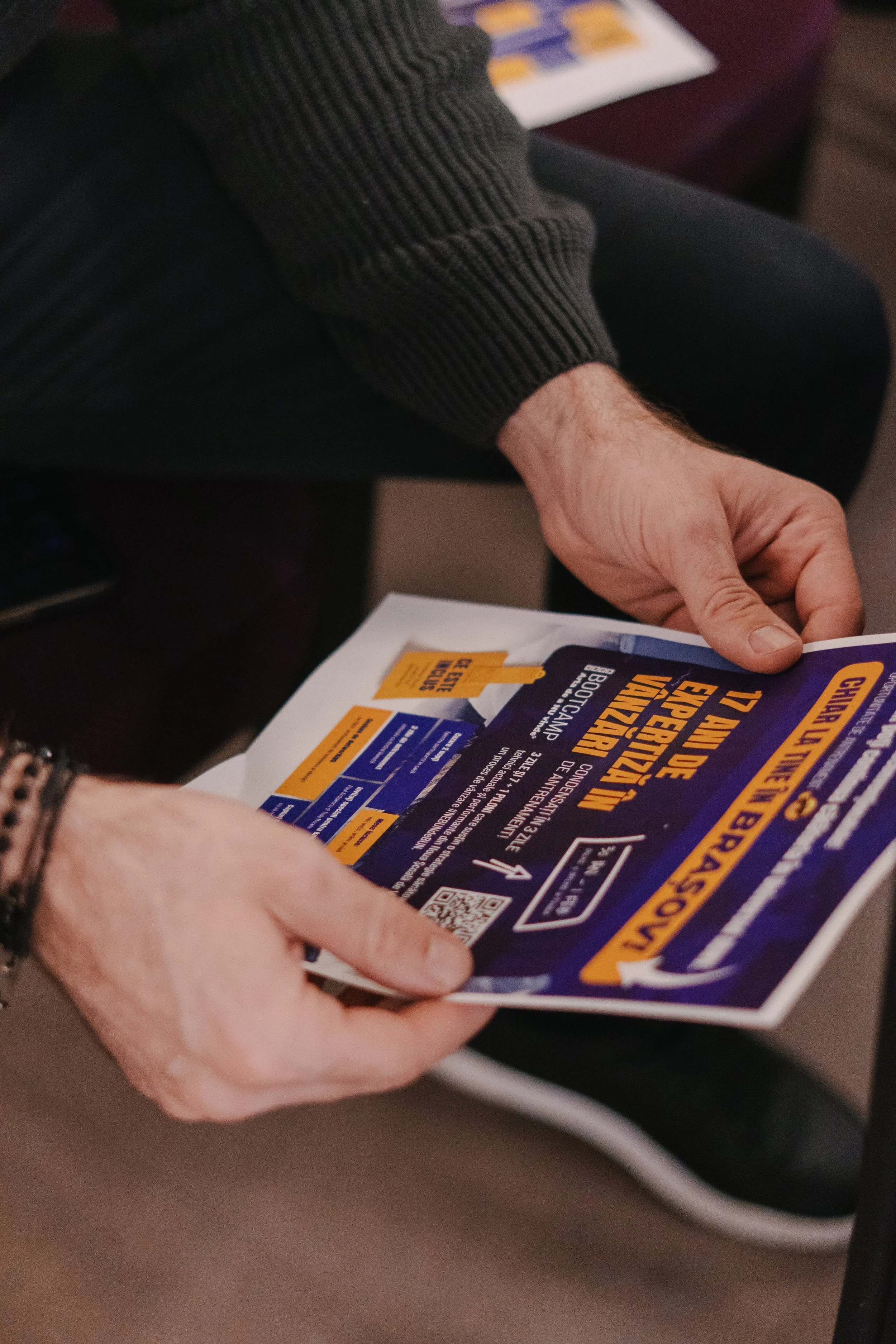 A person is holding a brochure or flyer with campaign information and a QR code, promoting voting in an upcoming election.