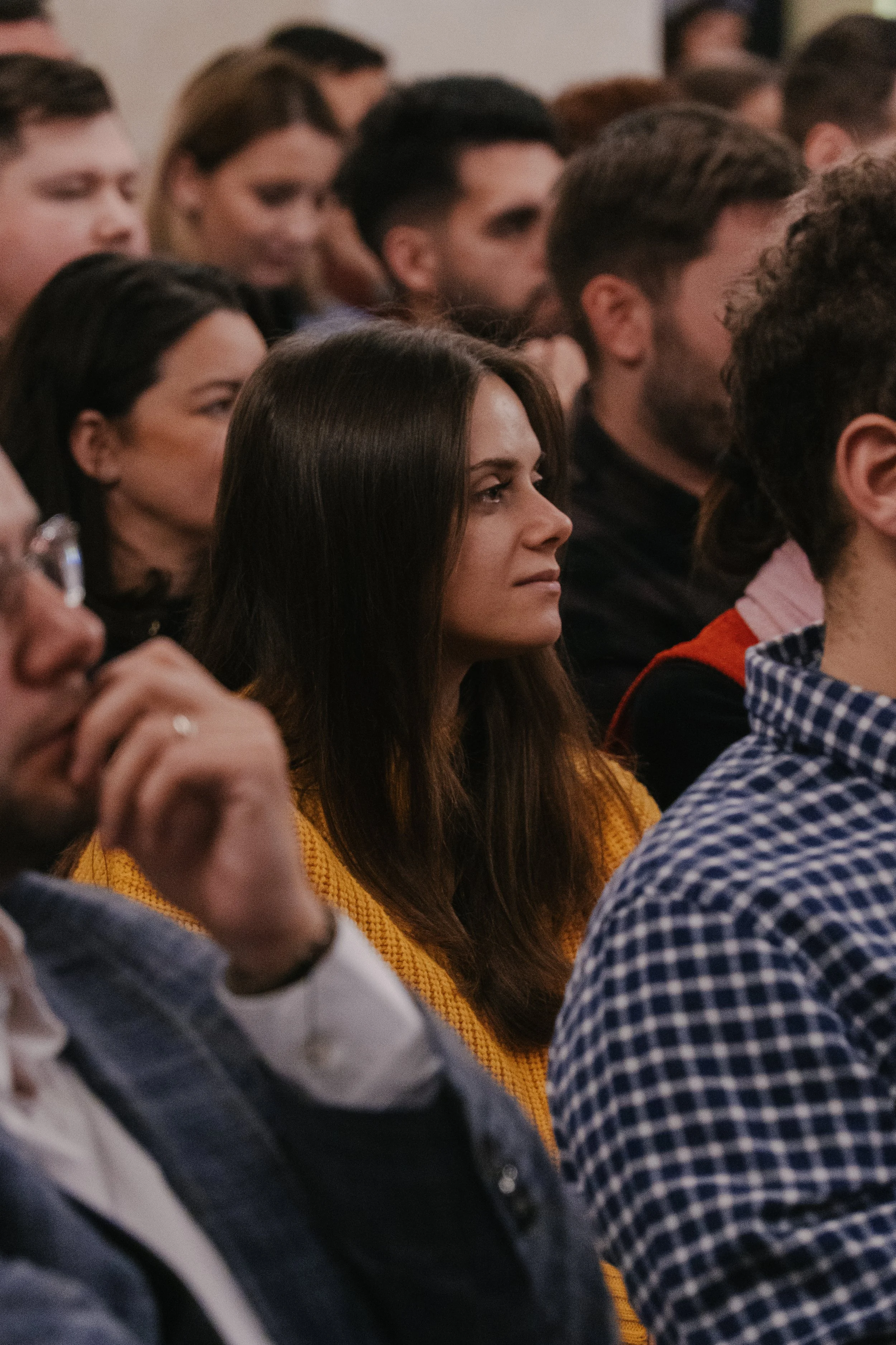 A crowd of people attending a presentation or lecture, focused and listening attentively.