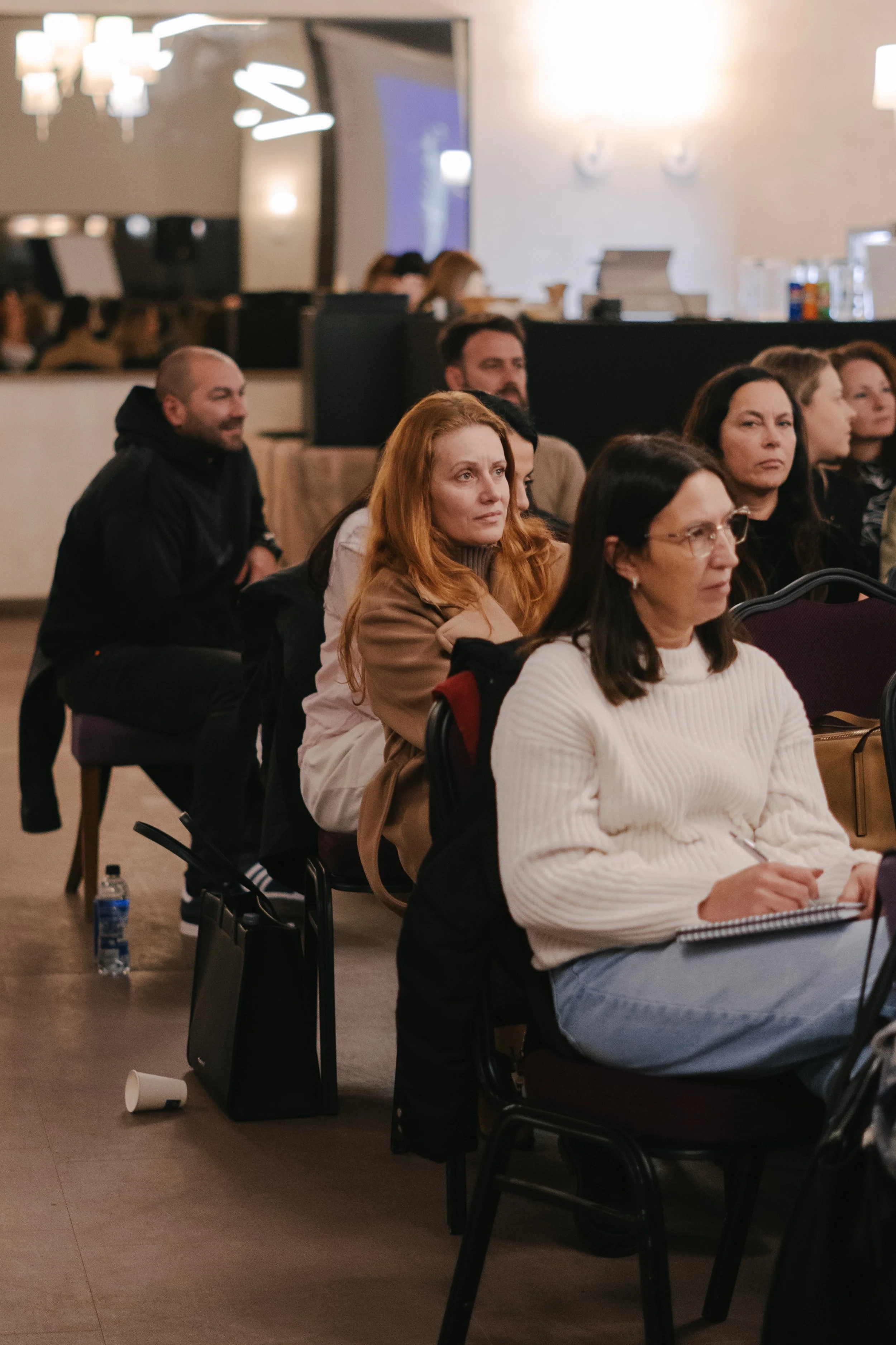Group of people sitting in a conference room, attentively listening to a presentation.
