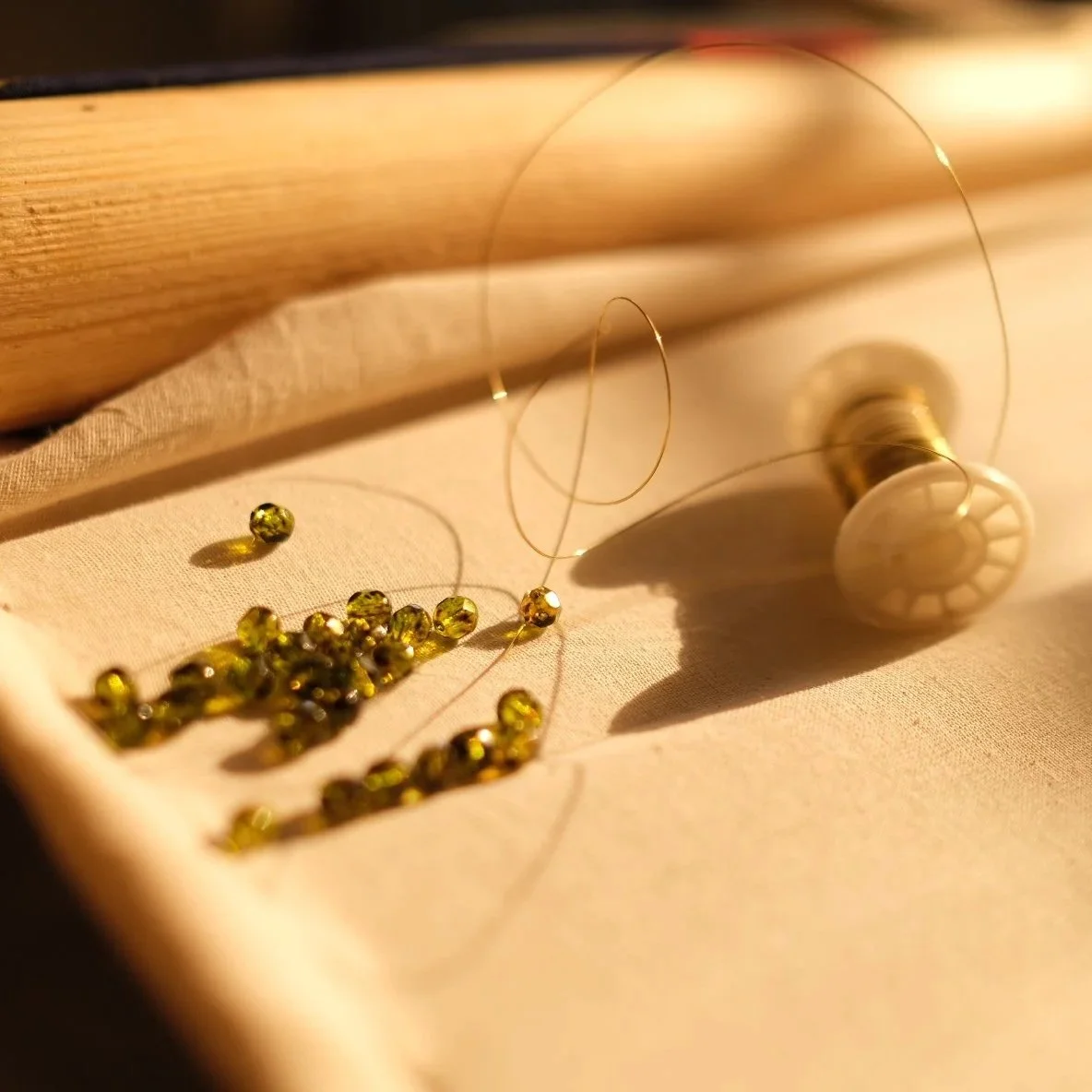 Des perles jaunes, une bobine de fil et un objet en bois avec un fil métallique