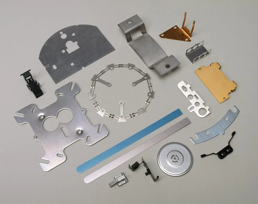 Various small metal and plastic parts and brackets arranged on a white background, possibly components for a mechanical or electronic device.
