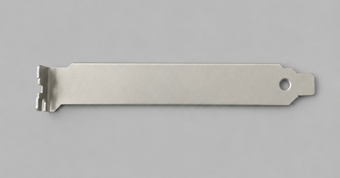 A metal razor blade with a textured grip, a hole on the right end, and notches on the left end, lying on a light gray background.
